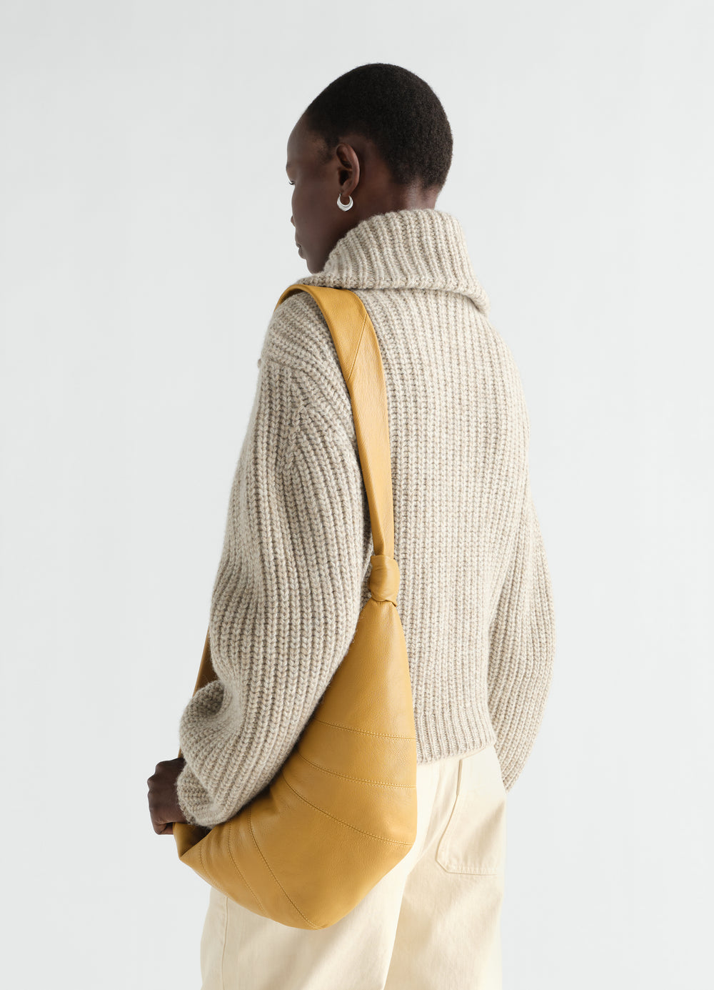 Medium Croissant Bag in yellow goat leather by LEMAIRE worn by model from back side with beige knit sweater