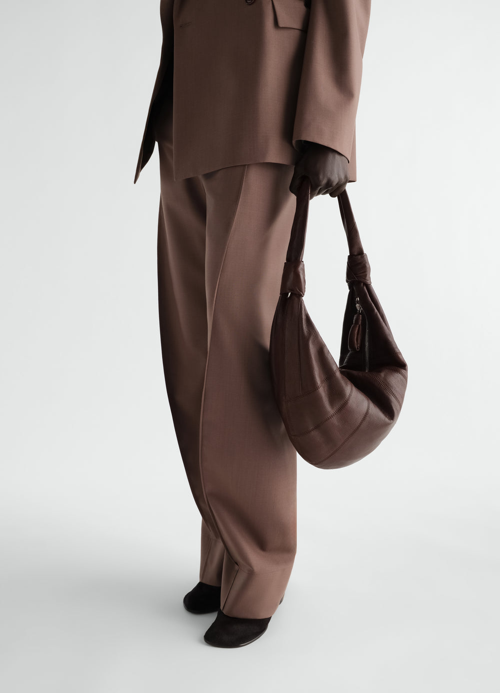 Sac Fortune Croissant en cuir de chèvre, coloris marron foncé, porté par un mannequin, vue de profil