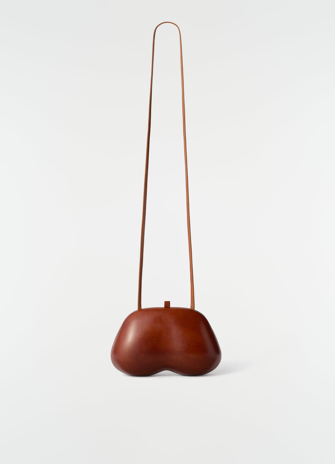 Fesses clutch bag in brown patinated calfskin leather with long strap by LEMAIRE on white background