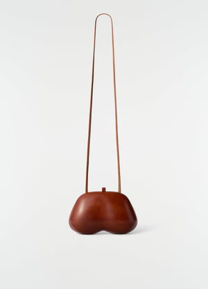 Fesses clutch bag in brown patinated calfskin leather with long strap by lemaire on white background