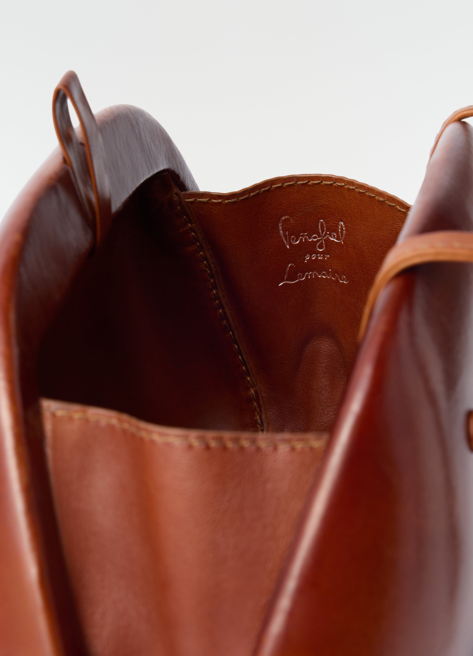 Fesses clutch in brown patinated calfskin by lemaire close-up detail of interior stitching and logo
