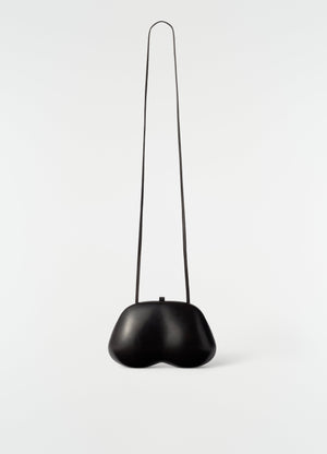 Fesses clutch in black patinated calfskin with long strap lemaire front on plain white background