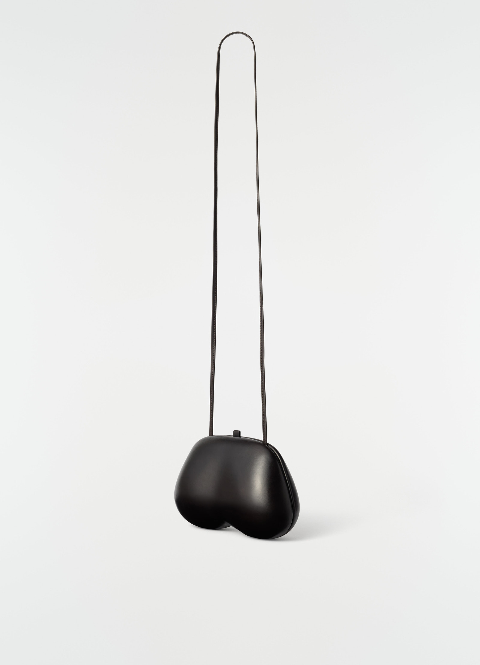 Fesses clutch in black patinated calfskin leather with long strap lemaire plain white background