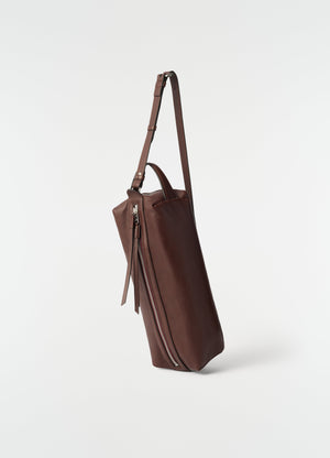Care shoulder bag in brown nappa lambskin leather by lemaire side view with zipped detail on plain white background