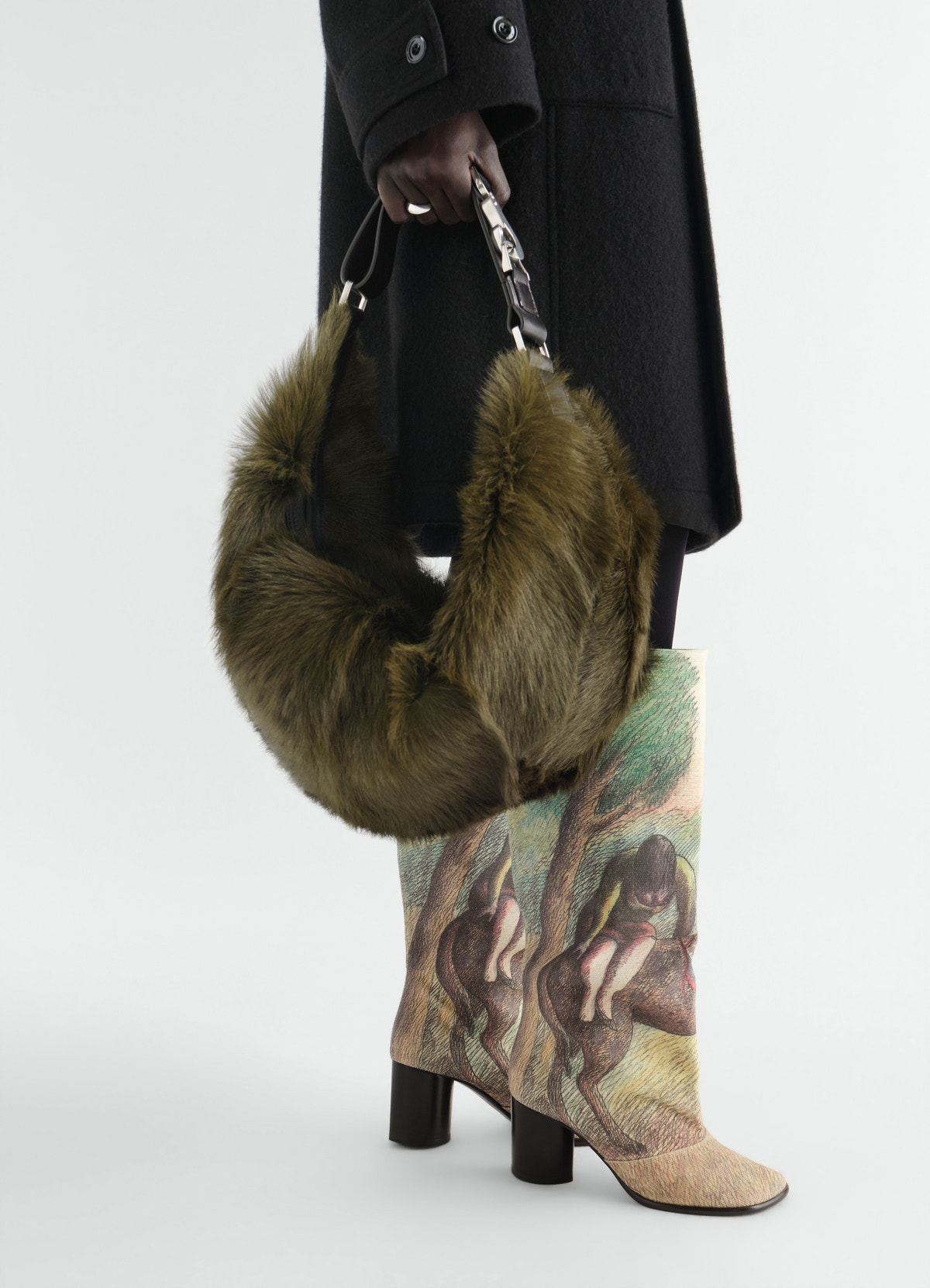 Quiver clip bag in olive fur long-hair goat leather held by model wearing printed boots lemaire styled look