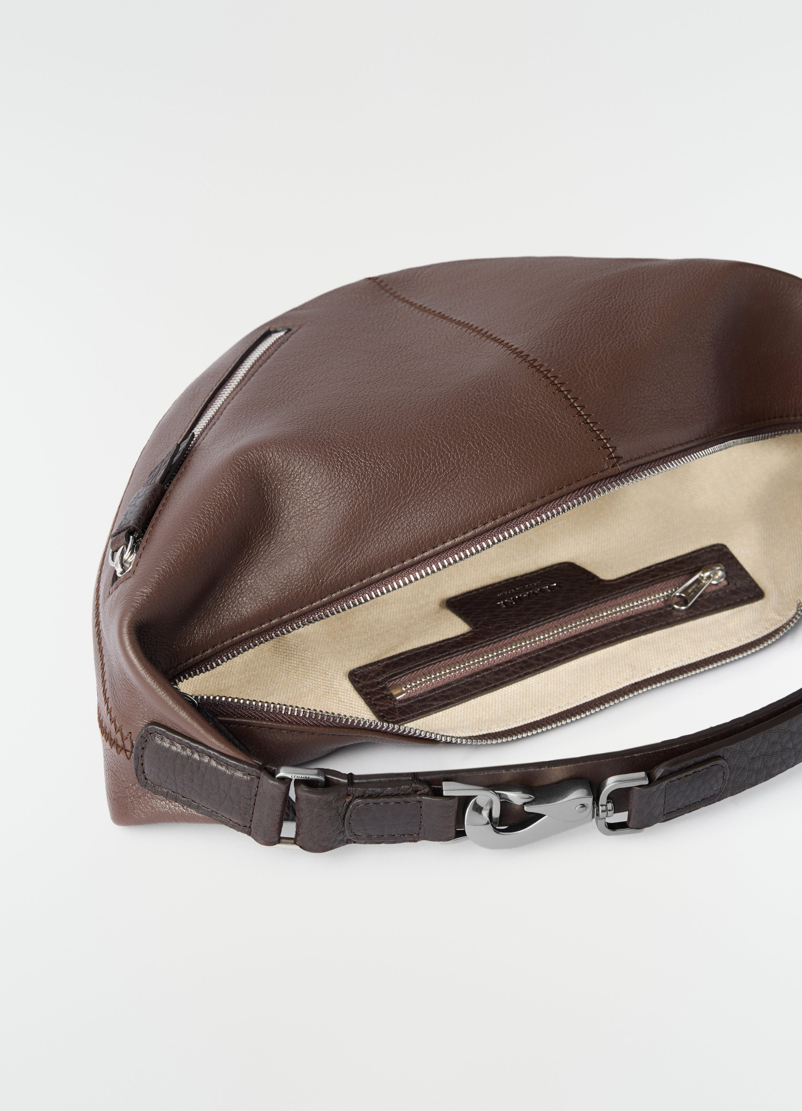 Mini quiver clip bag lemaire in brown grained buffalo leather with beige interior, close-up of open zipper pouch and strap