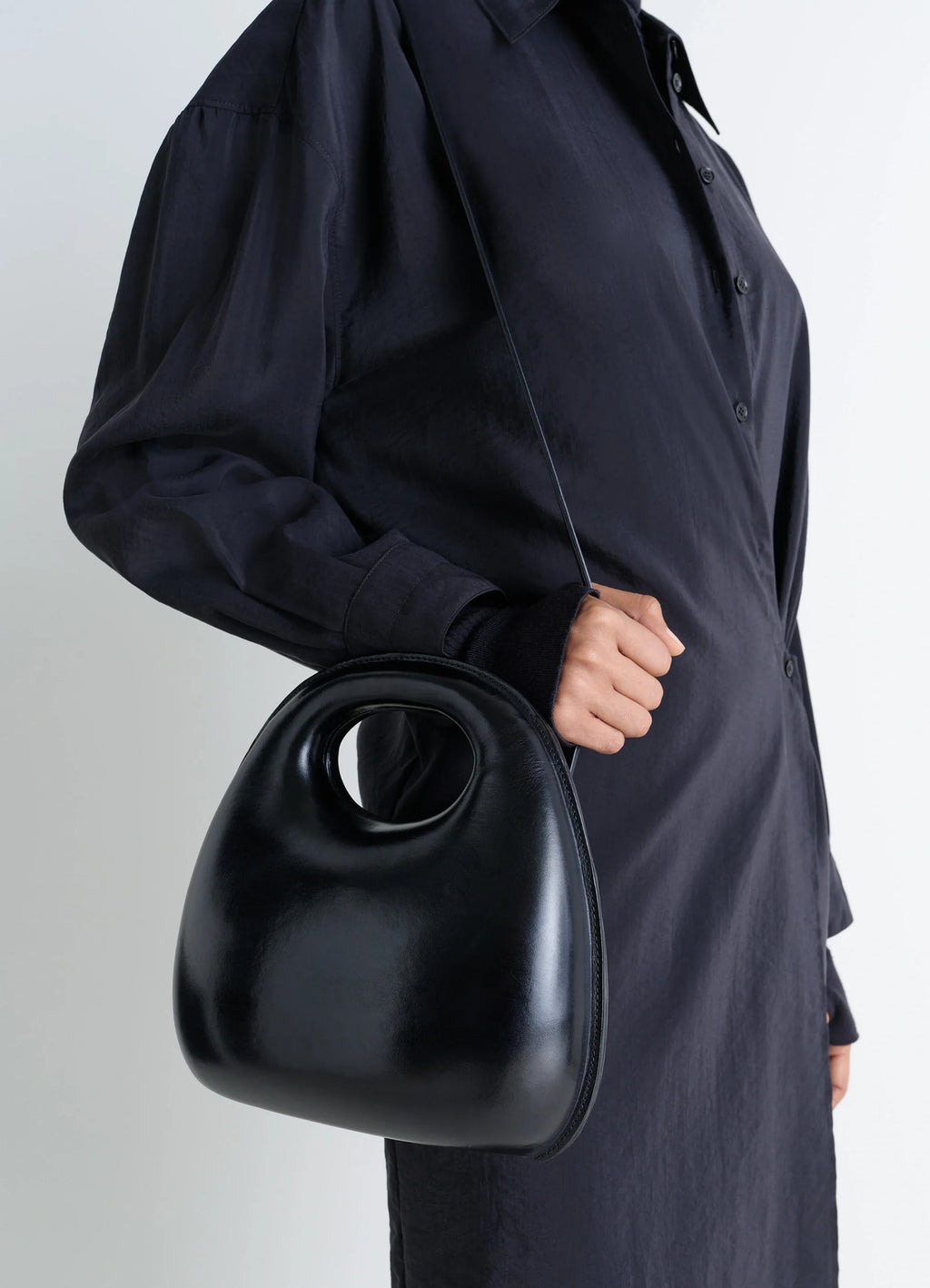 Lemaire Egg Bag in Black Patinated Leather, model shot, side view cross-body carry