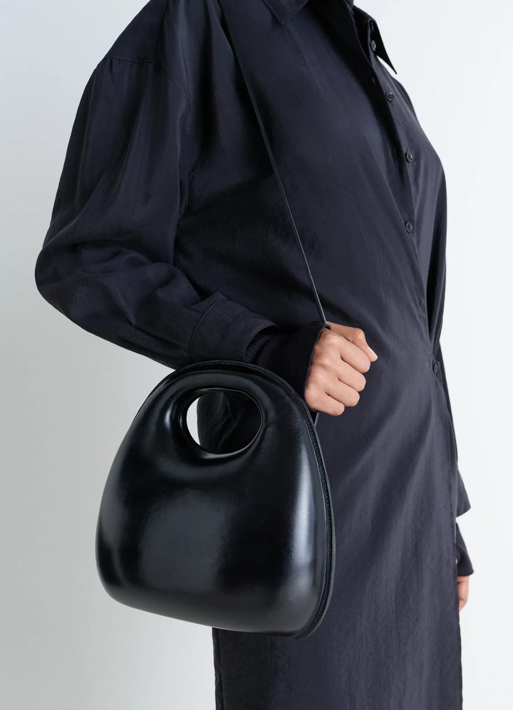 Lemaire Egg Bag in Black Patinated Leather, model shot, side view cross-body carry