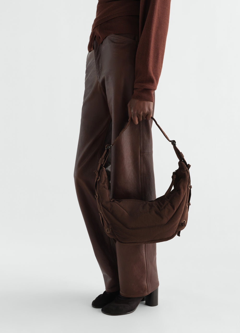 Small soft brown nylon canvas Game Bag worn by model with leather trousers LEMAIRE side view