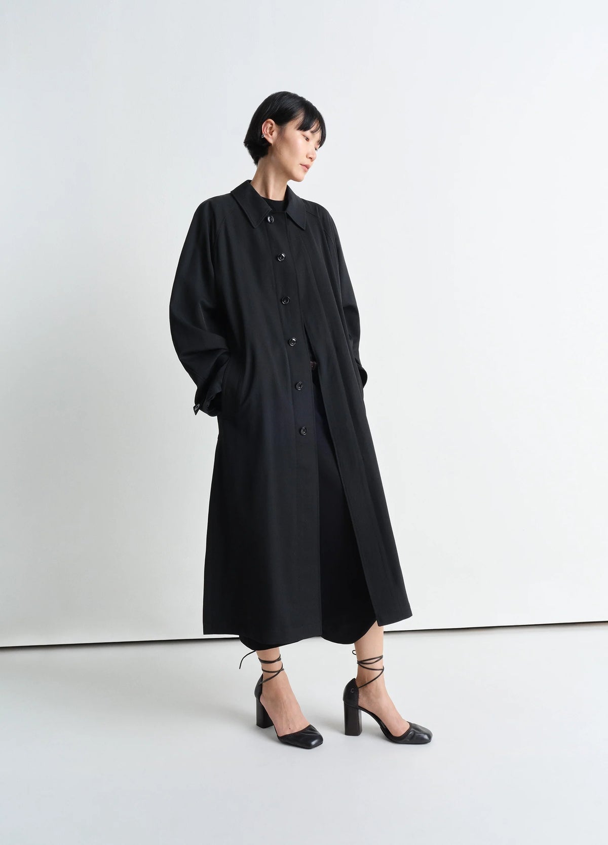 Light Slitted Overcoat in Black Wool Viscose Gabardine, model shot, Side view Long coat with buttons