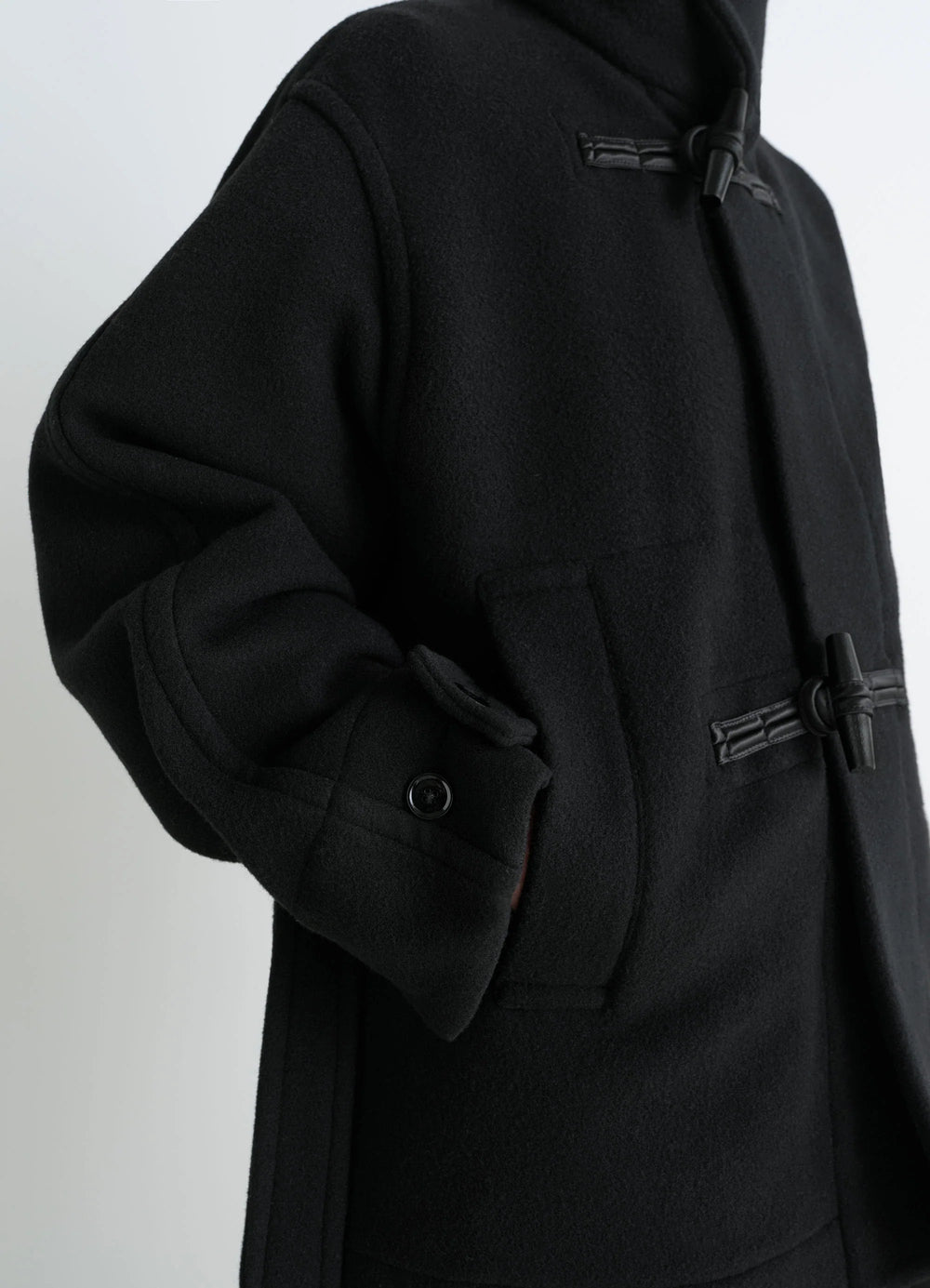 Lemaire Short Duffle Coat in Black Double-faced Wool, model shot, Side detail view Shiny piping, toggles