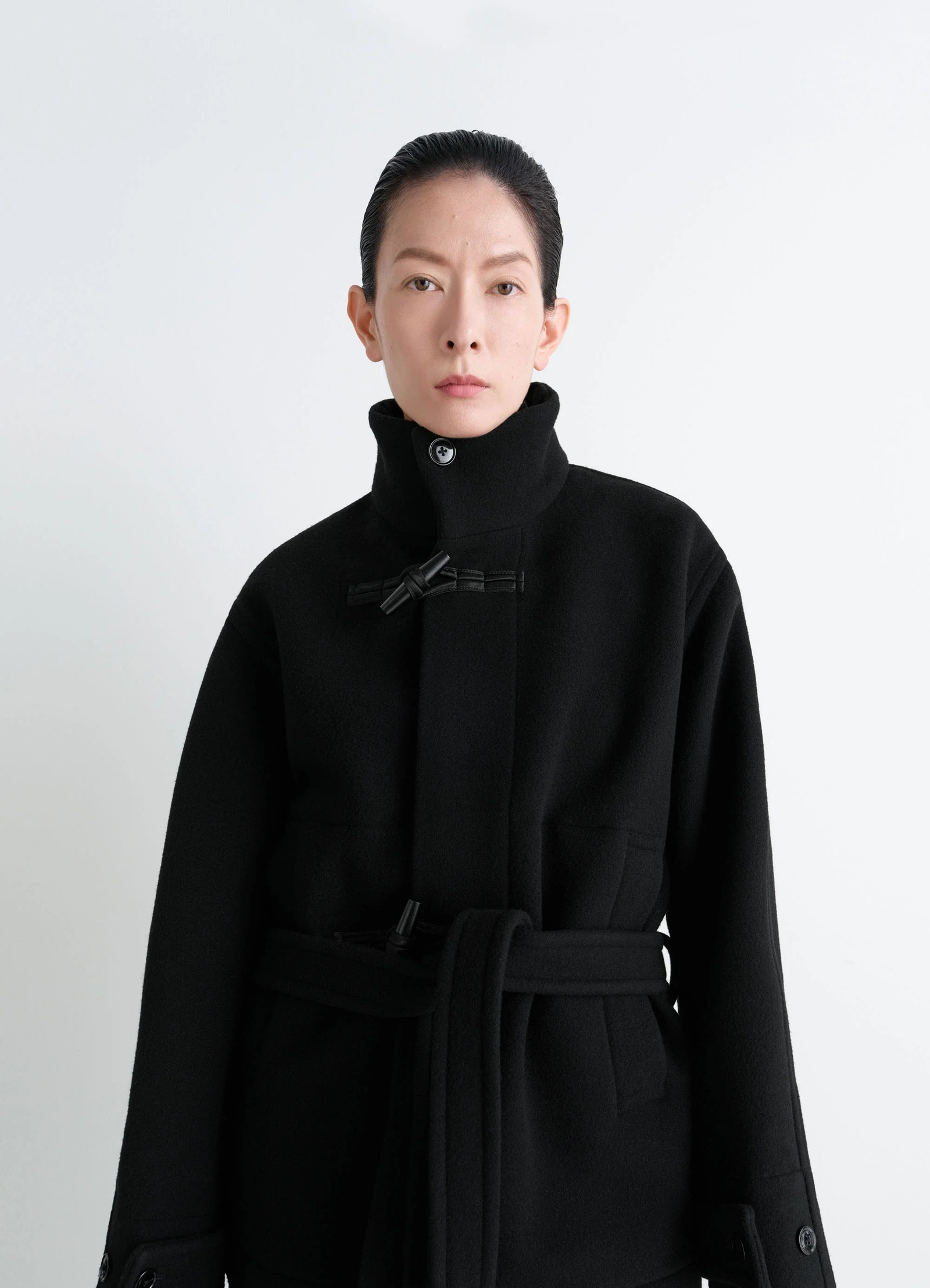 Lemaire short duffle coat in black double-faced wool, model shot, upper body front view high collar knot toggle