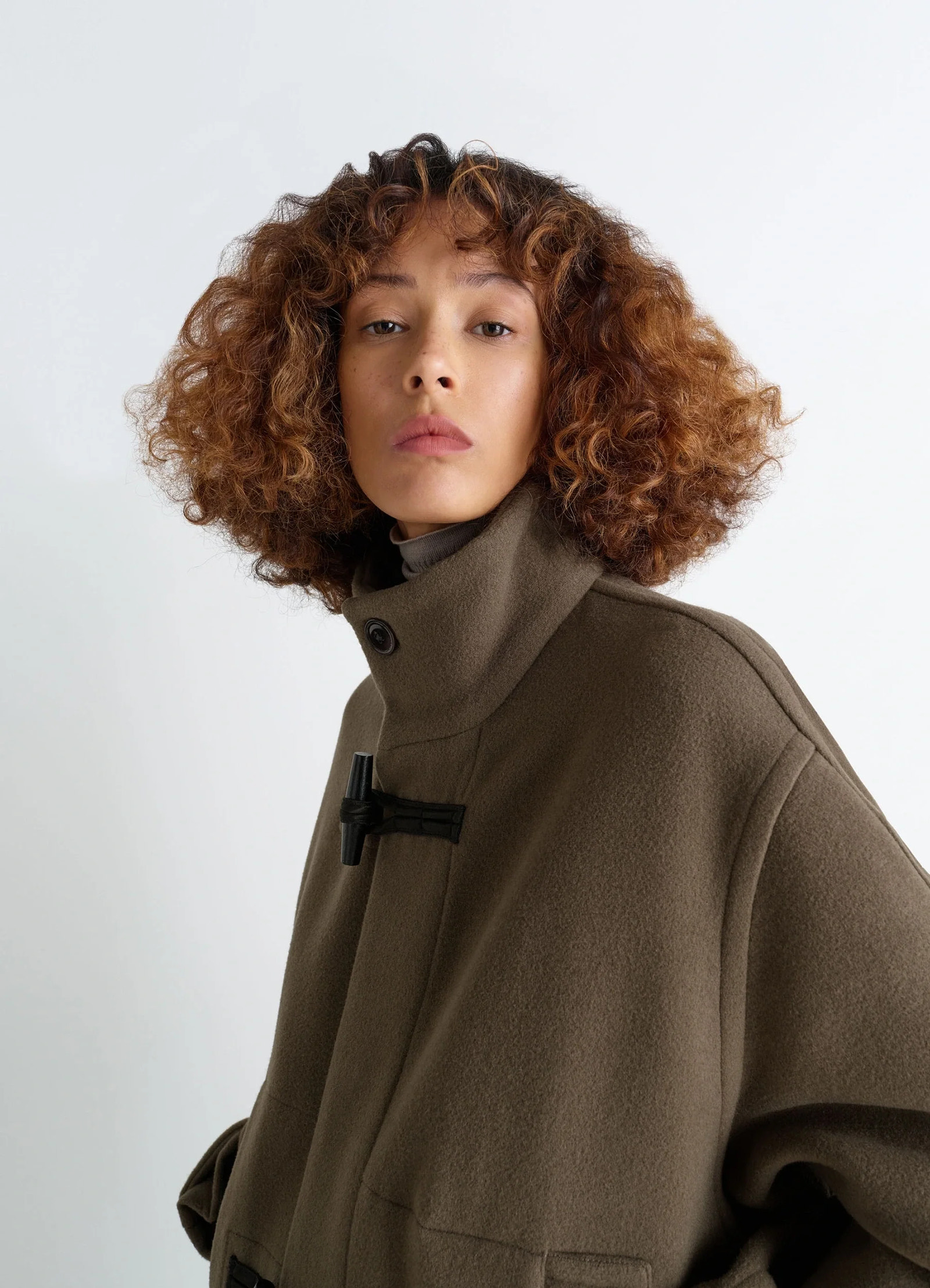 Lemaire short duffle coat in olive double-faced wool, model shot, three-quarter view buttoned high neck