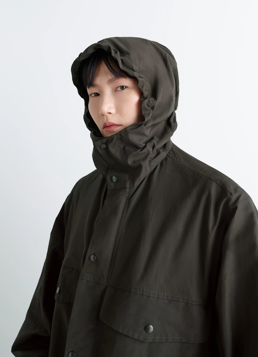 Lemaire Utility Raincoat in Khaki Linen Cotton Blend, model shot, close-up hooded view hooded design, protective flaps