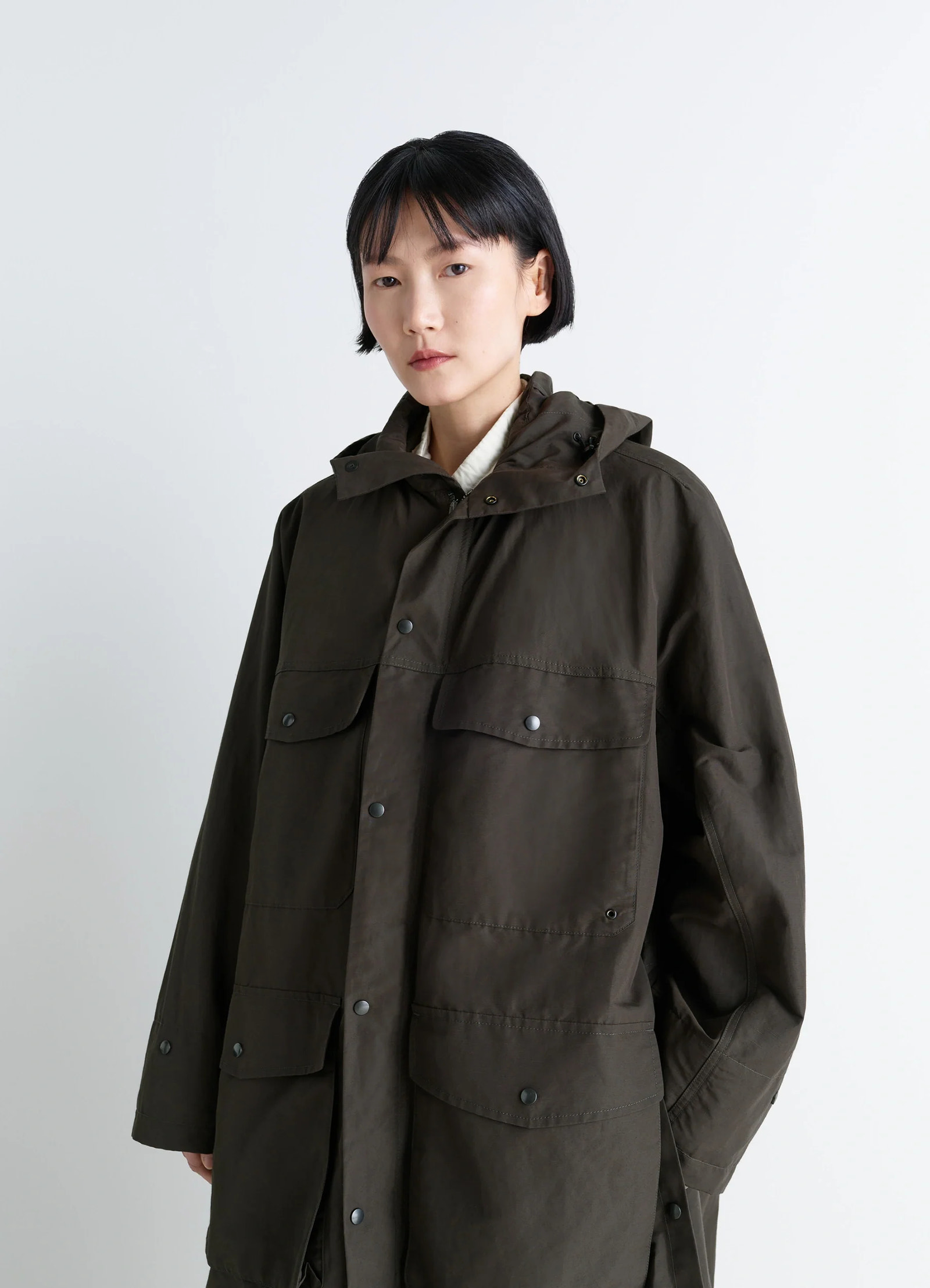 Lemaire utility raincoat in khaki linen cotton blend, model shot, detailed half-torso view pressed stud pockets, layered coll