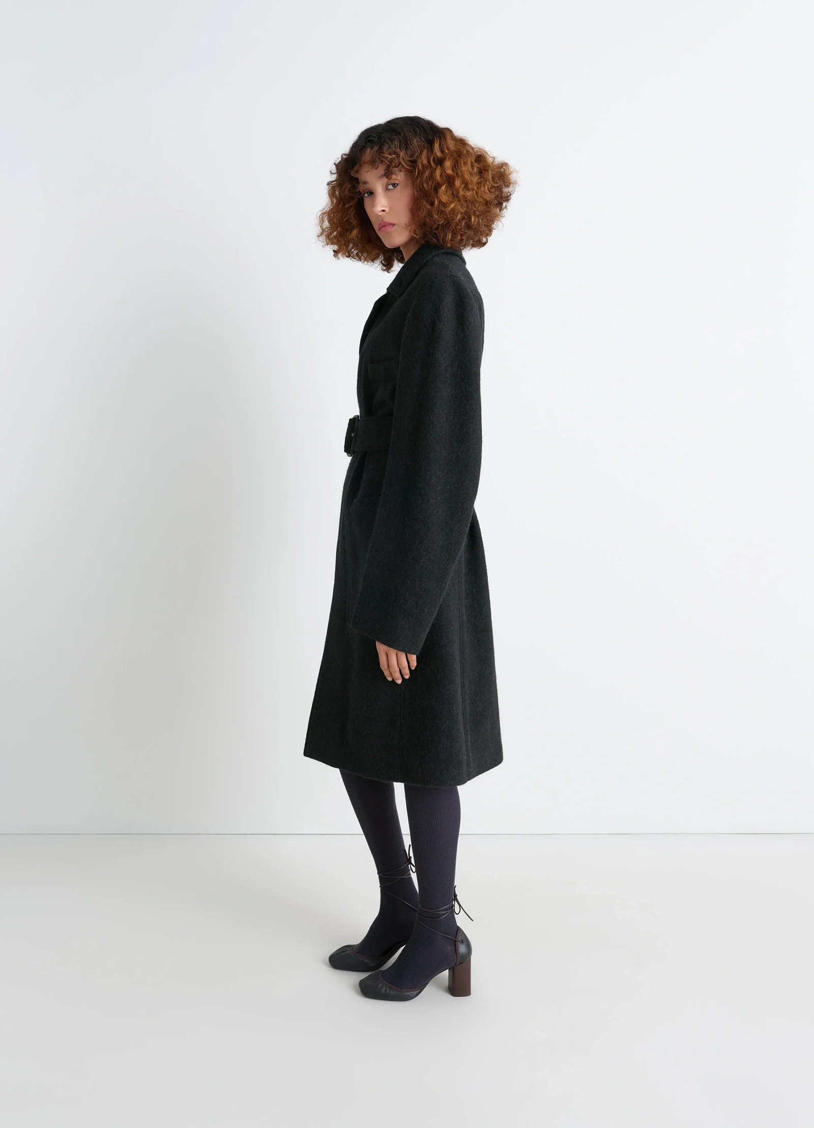 Belted tailored coat in deep charcoal wool alpaca, model shot, side view mid-length hem