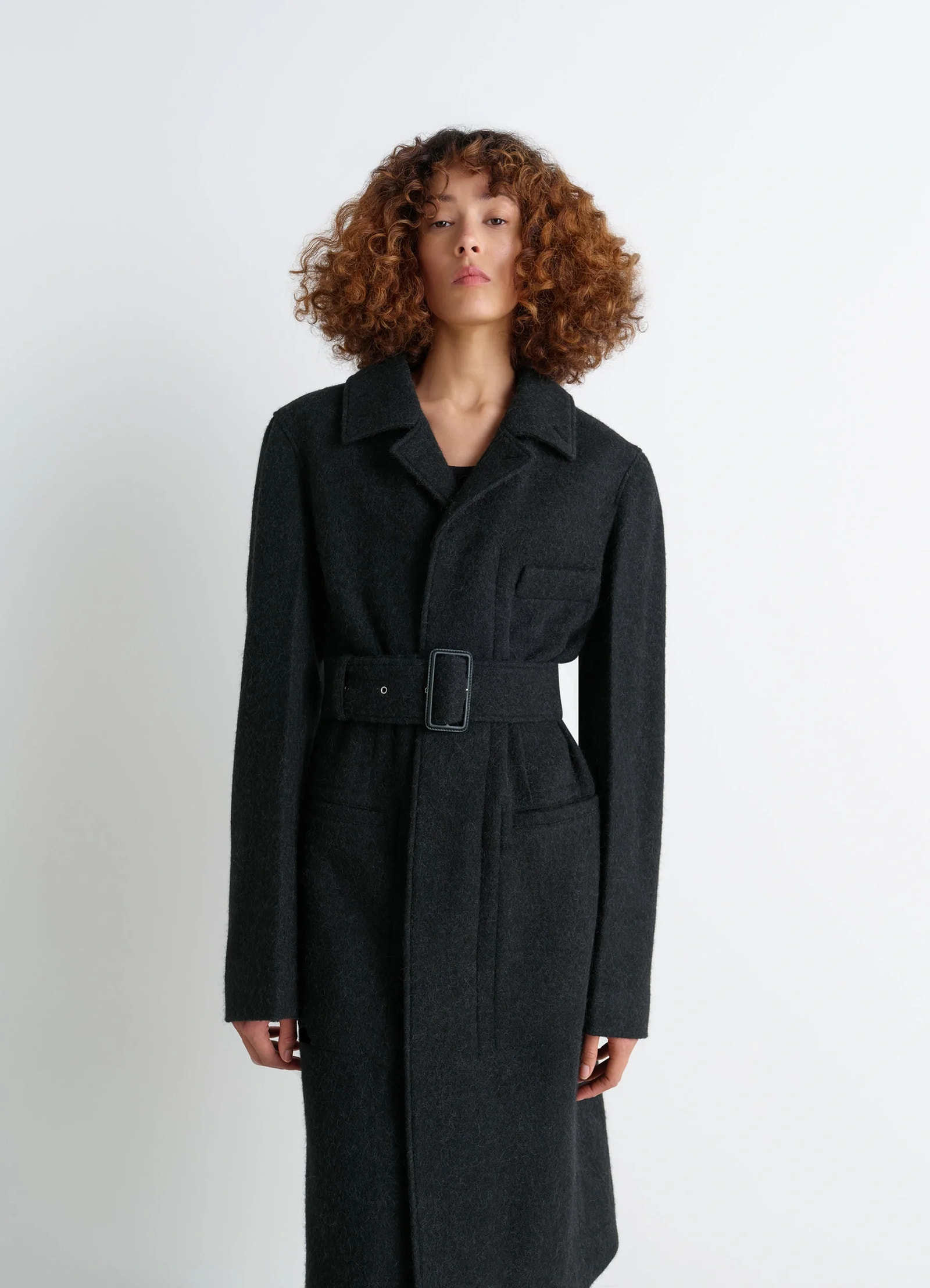 Belted tailored coat in deep charcoal wool alpaca, model shot, three-quarter view notch lapel, single pocket