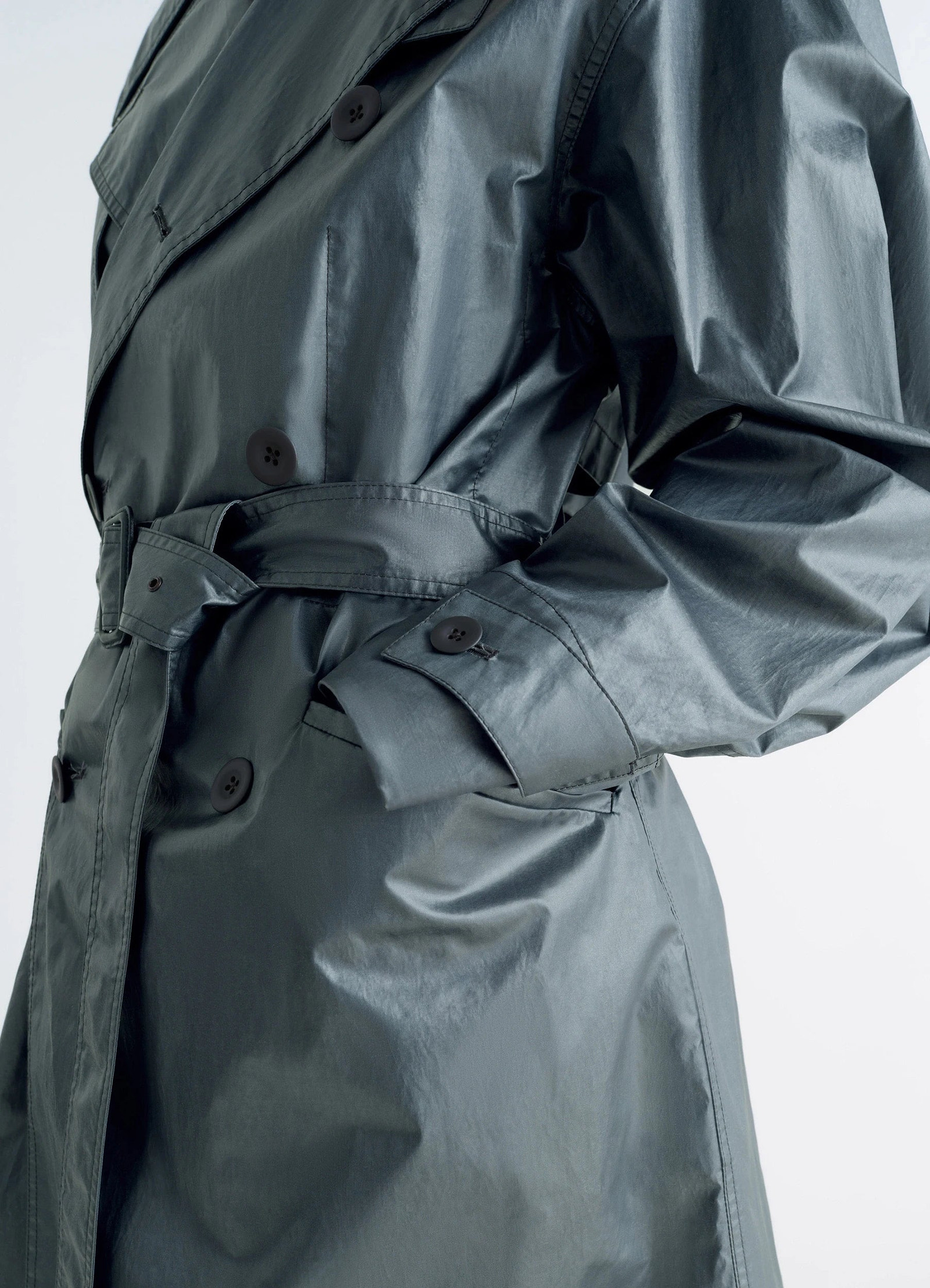 Oversized trench coat in metallic coated cotton, model shot, close-up waist view pocket detail, button cuffs