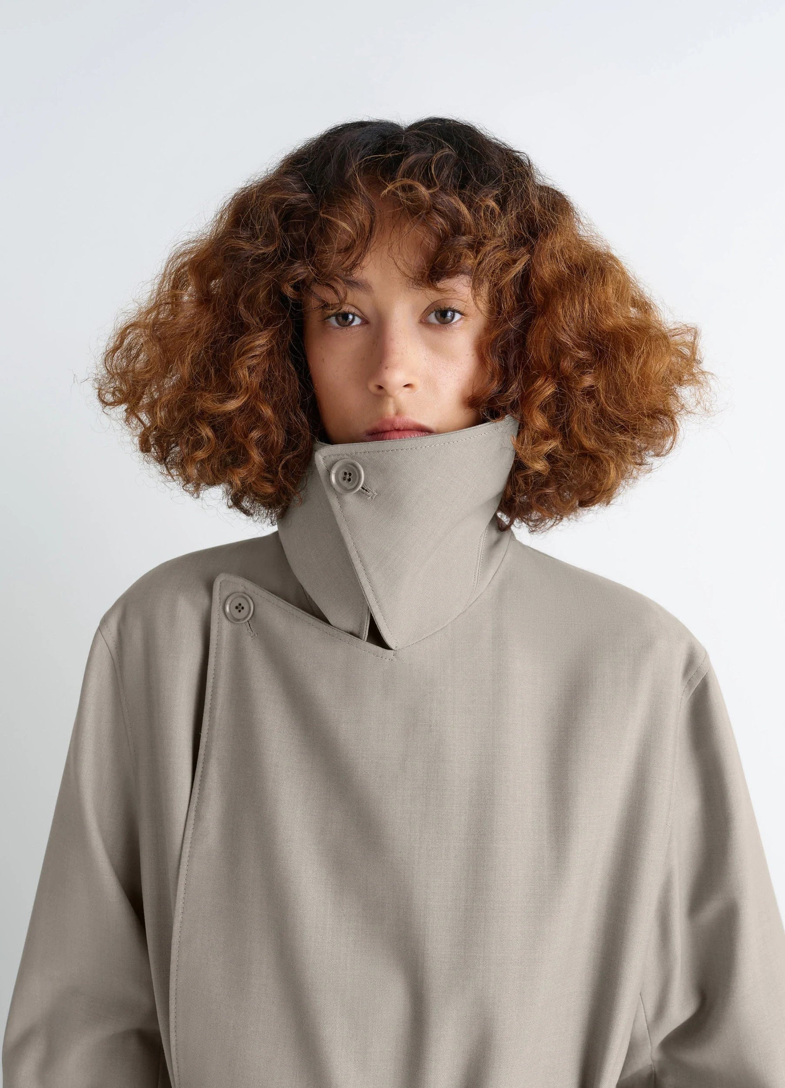 Lemaire trench coat in tropical wool-blend mottled, model shot, close-up portrait view high collar button detail