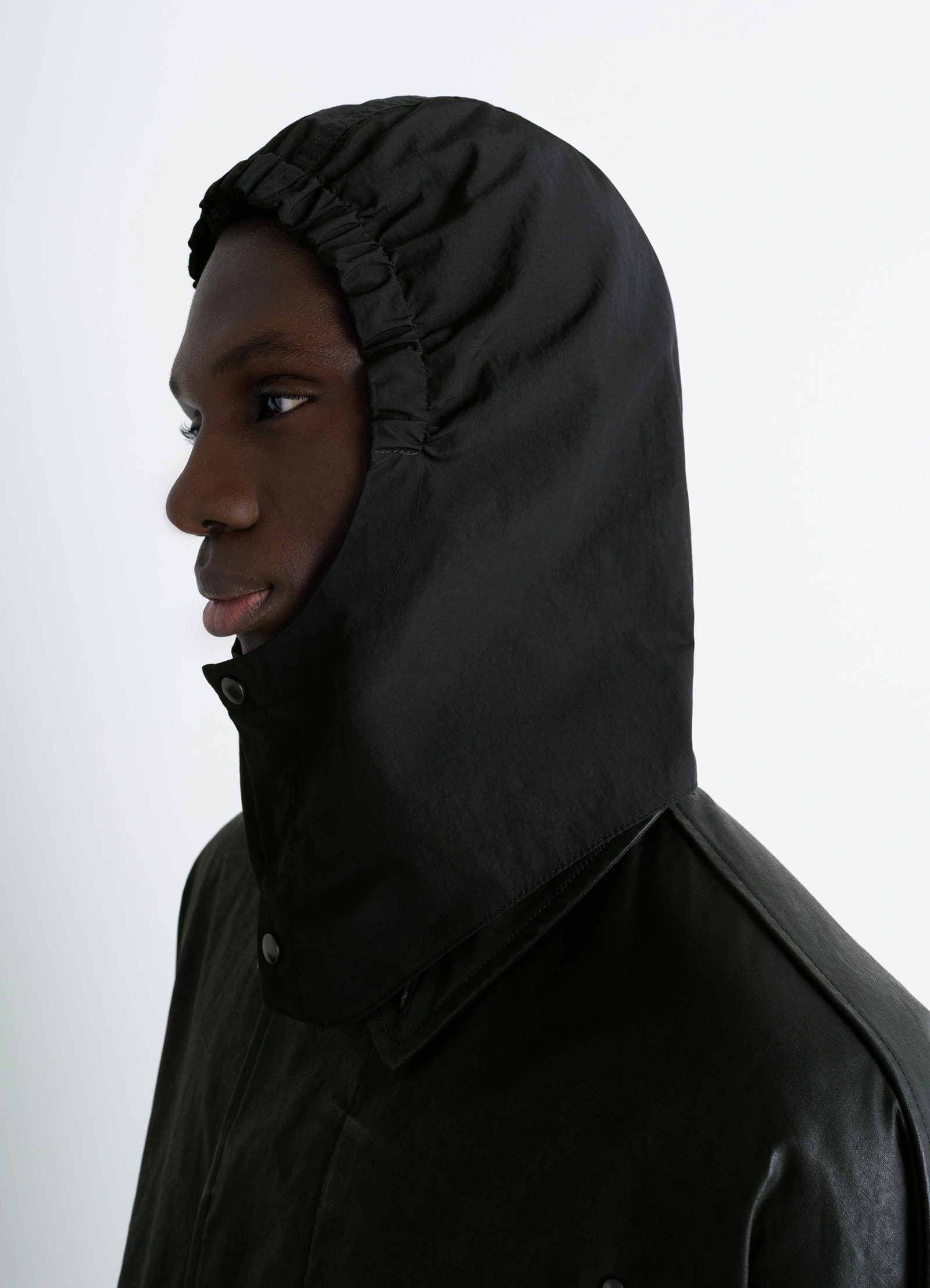 Hooded raincoat in water-repellent resinated cotton, model shot, side profile drawstring hood detail