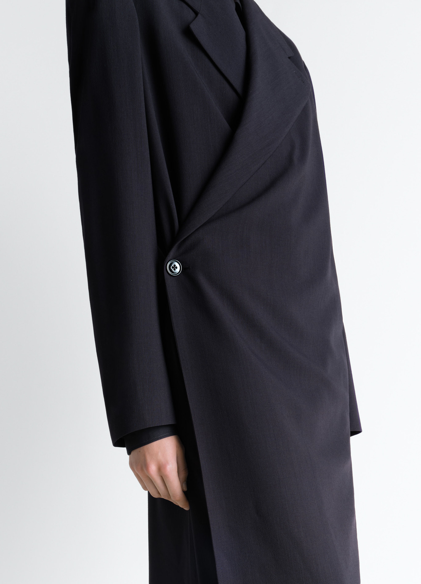 Wrap over coat in wool crepe in dark wool crepe, model shot, close up side view asymmetrical wrap detail
