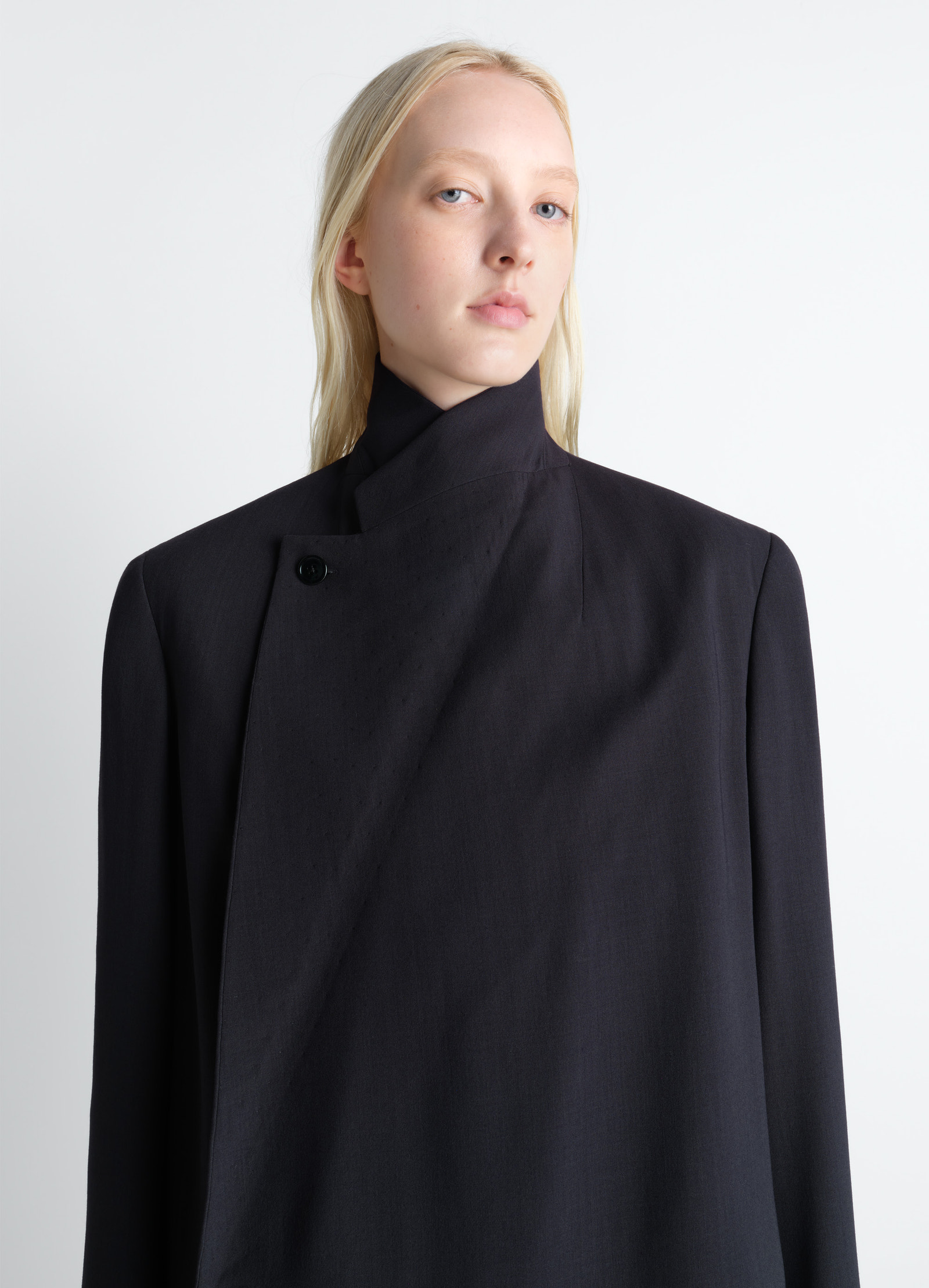 Wrap over coat in wool crepe in dark wool crepe, model shot, close-up front view high neck button detail