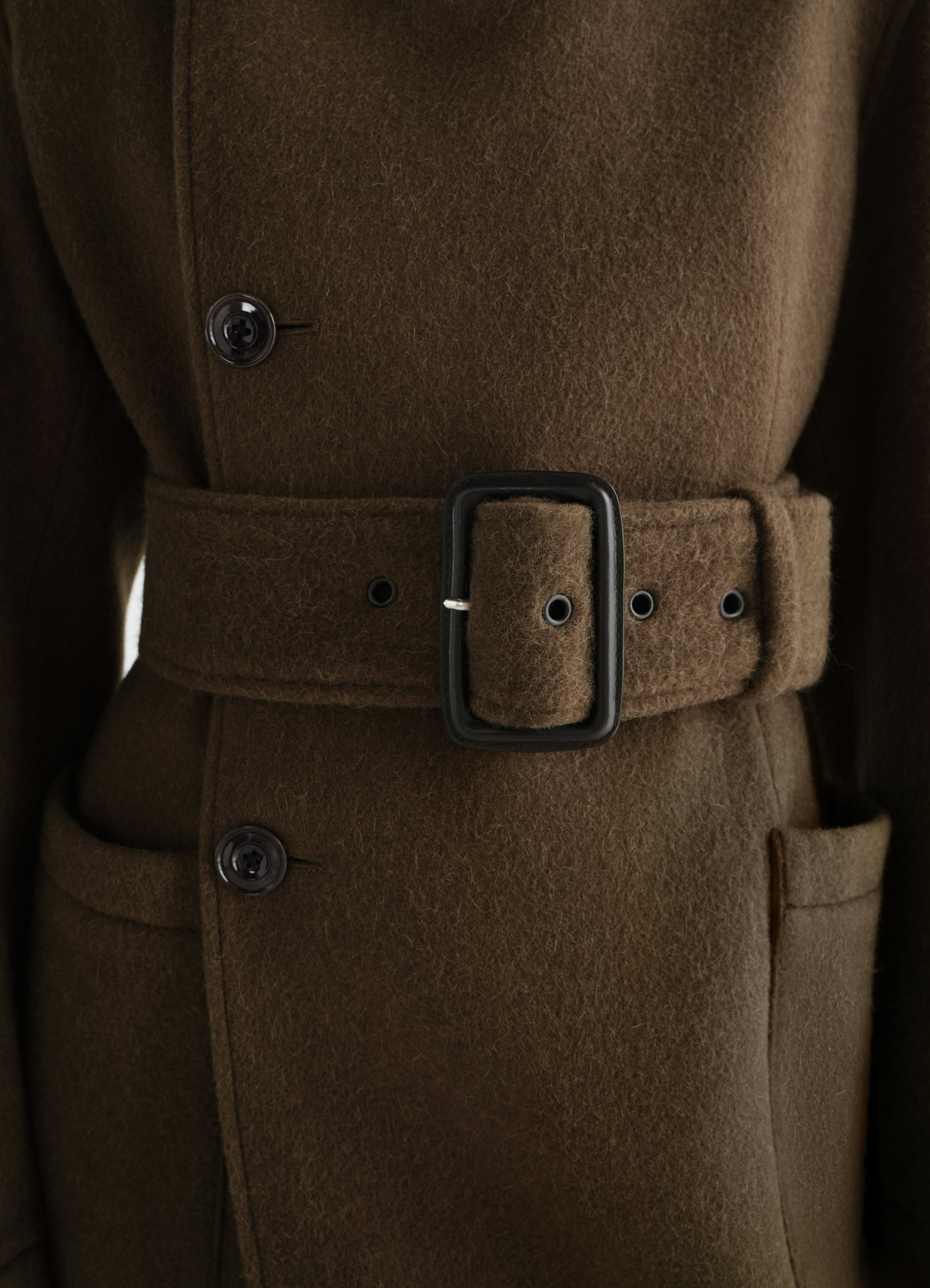 Fitted brown wrap coat in felted wool alpaca blend with belt and buttons worn by model lemaire close-up