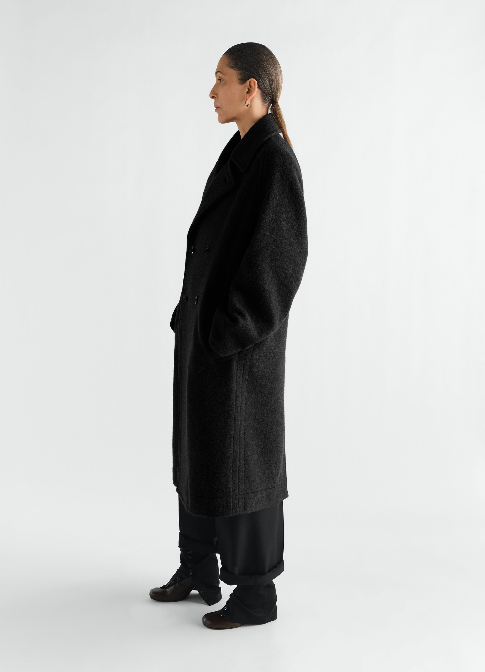 Manteau à double boutonnage en mélange de laine et alpaga feutré, coloris noir, porté par un mannequin, vue de profil