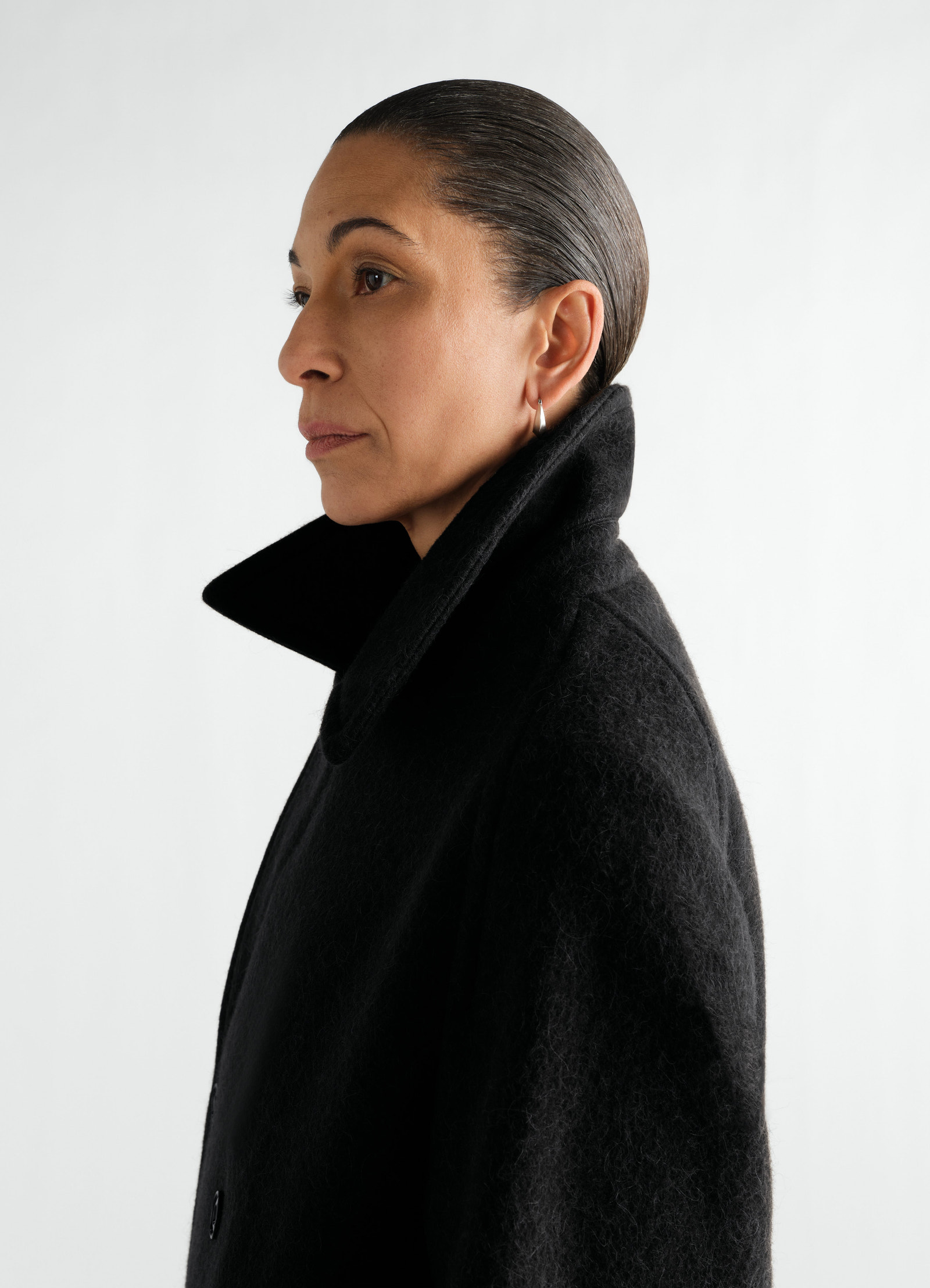 Manteau à double boutonnage en mélange de laine et alpaga feutré, coloris noir, porté par un mannequin, vue de profil, col visible