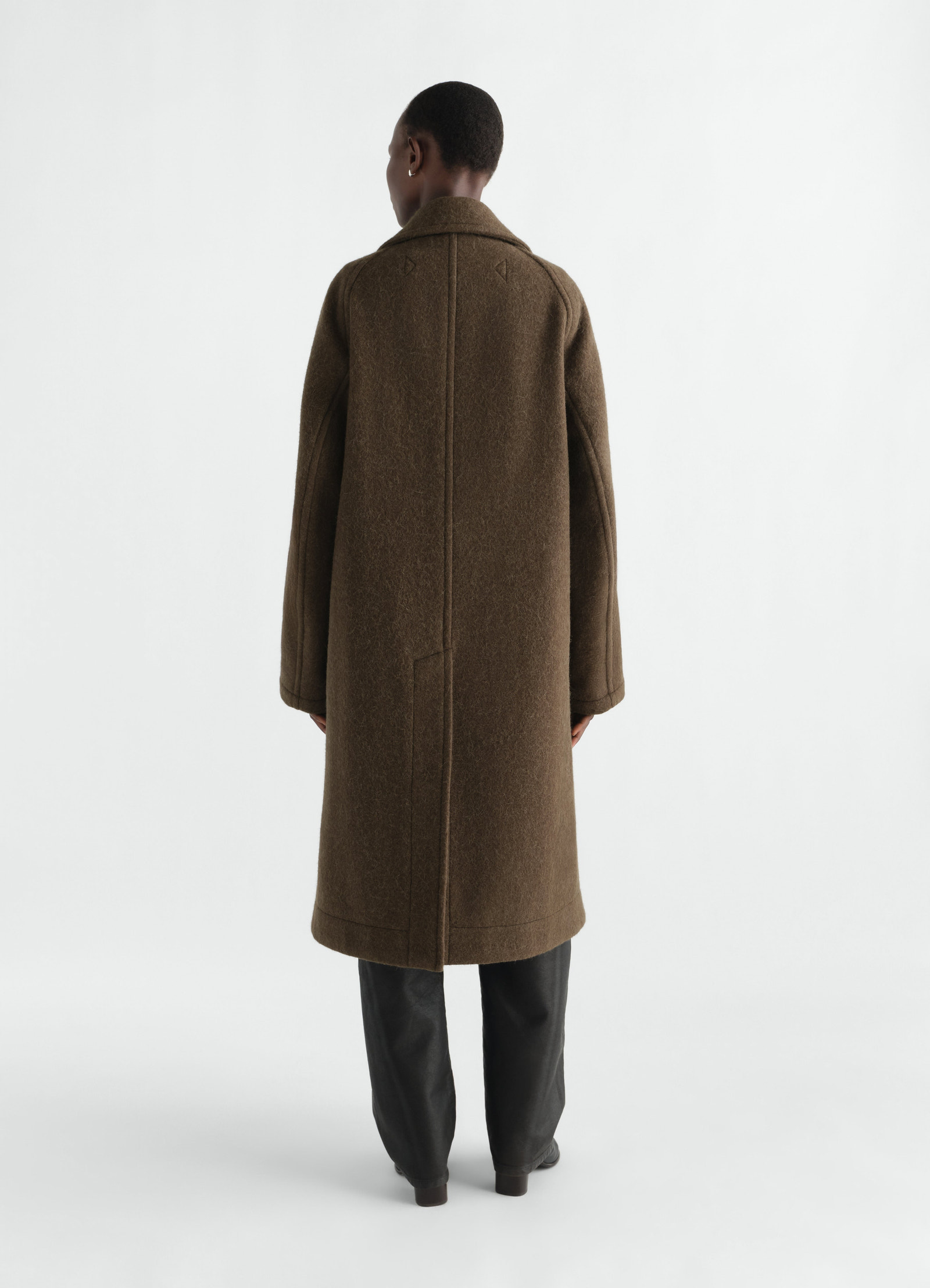 Double-breasted brown wool alpaca blend coat by lemaire worn by model back view with collar and long sleeves