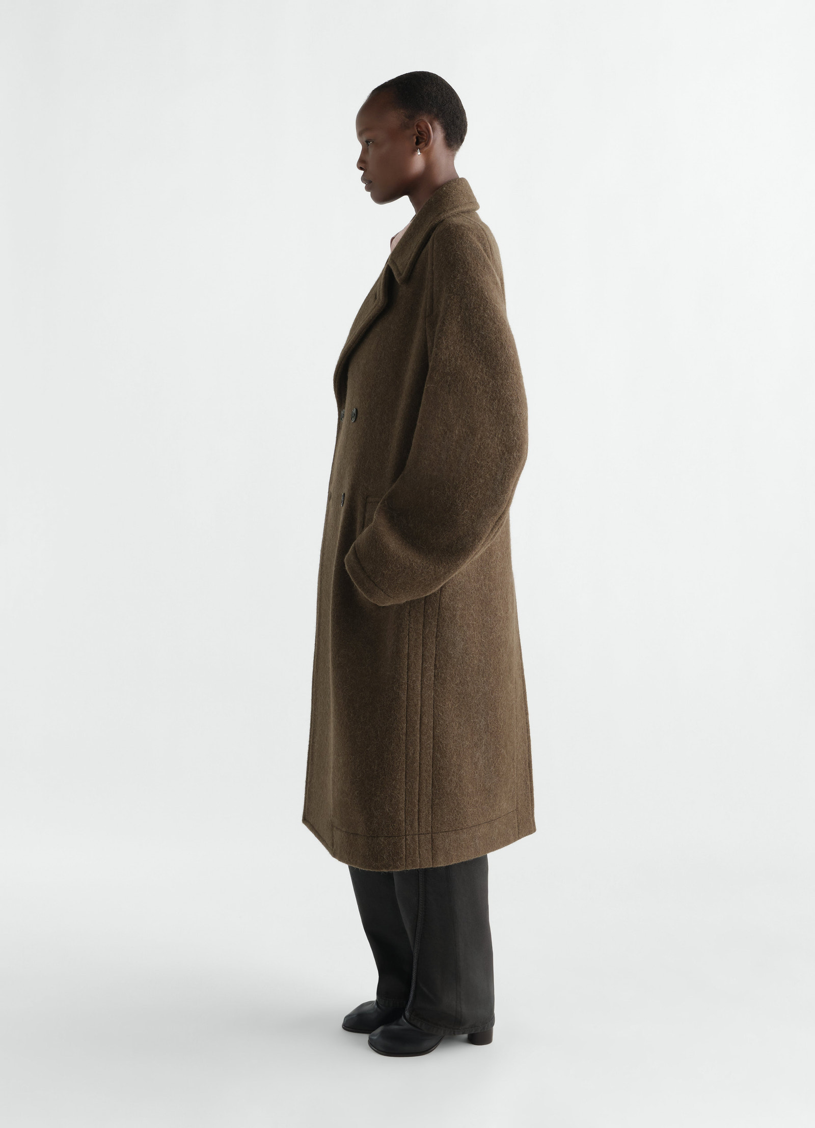 Double-breasted brown felted wool alpaca coat by lemaire worn by model side view