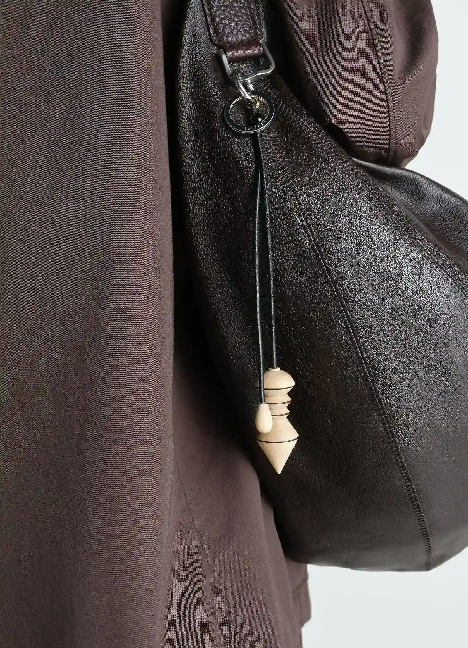 Pendulum bag charm in wood, model shot, side view attached to leather bag
