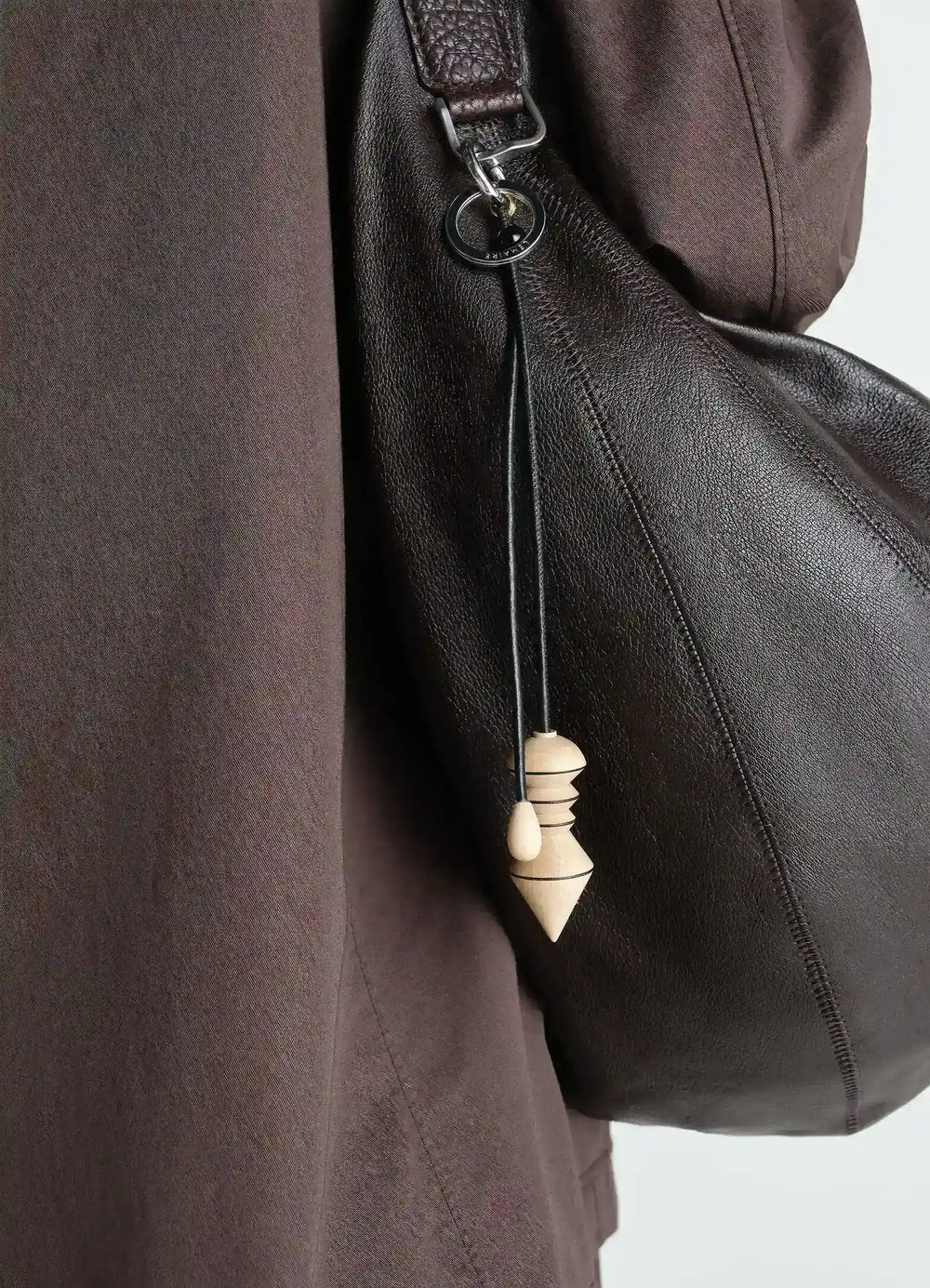 Pendulum Bag Charm in Wood, model shot, side view attached to leather bag