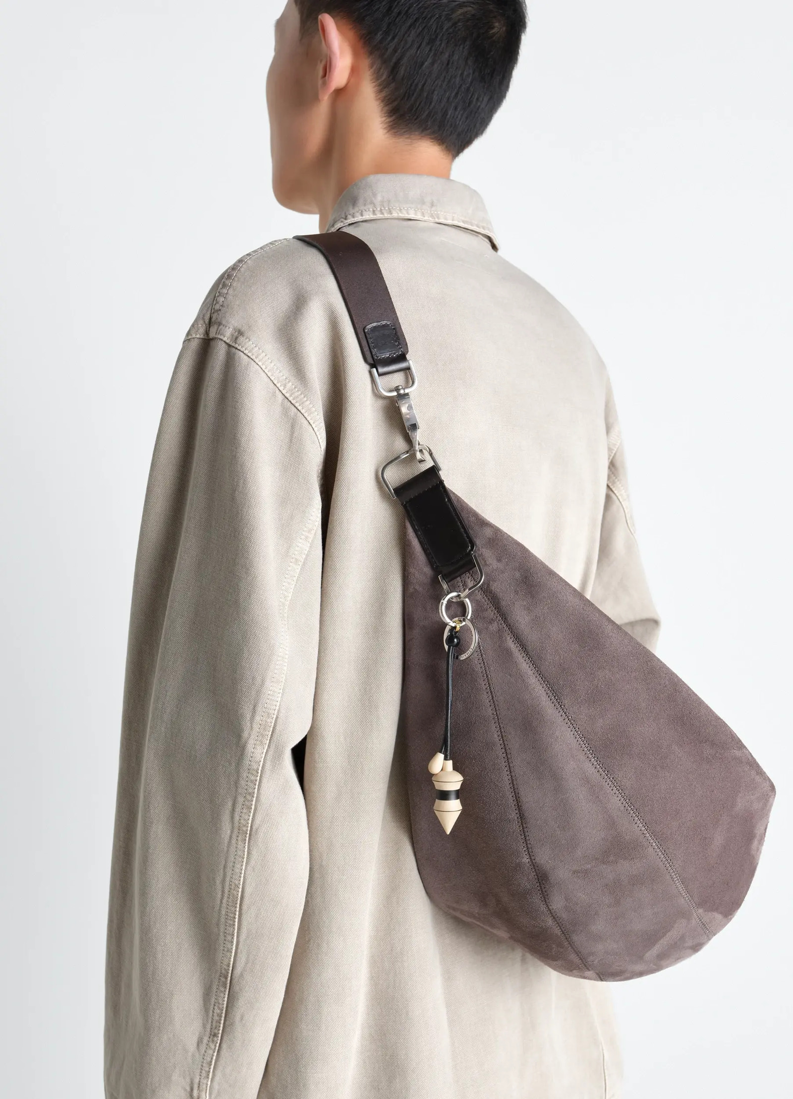 Pendulum bag charm in black stripes wood, model shot, back view over shoulder styling