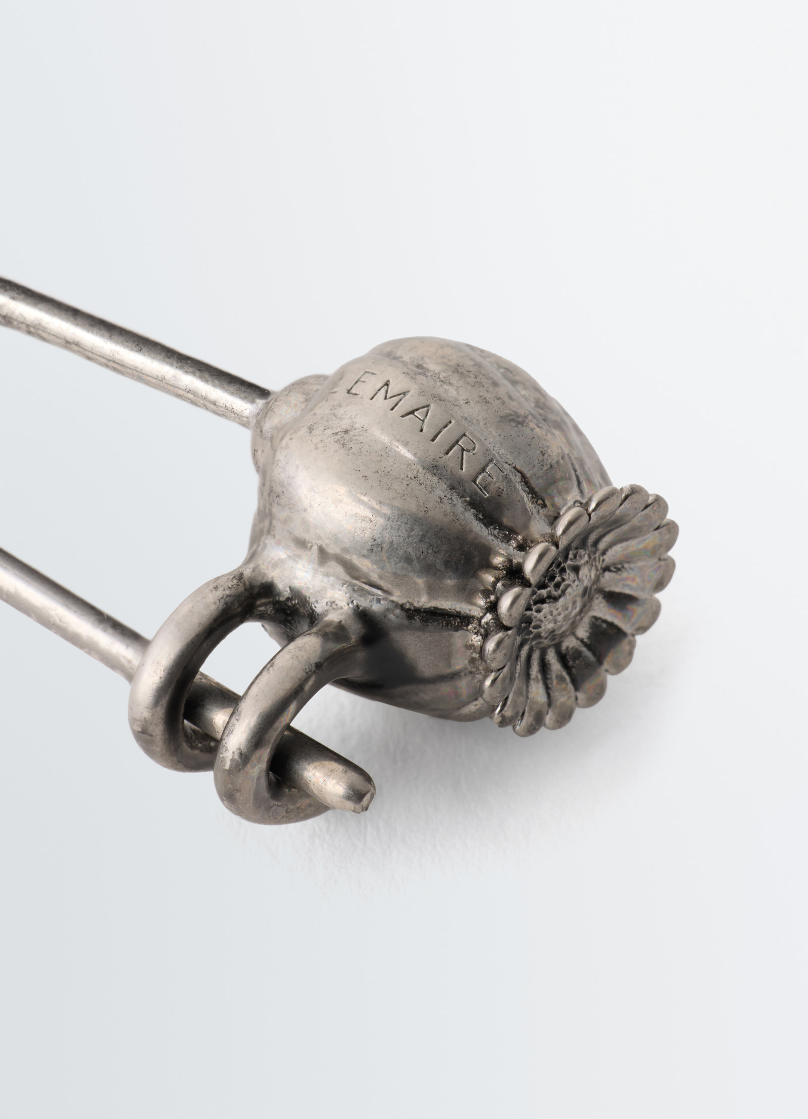 Thistle pin bag charm in silver metal with engraved lemaire logo close-up detail on white background