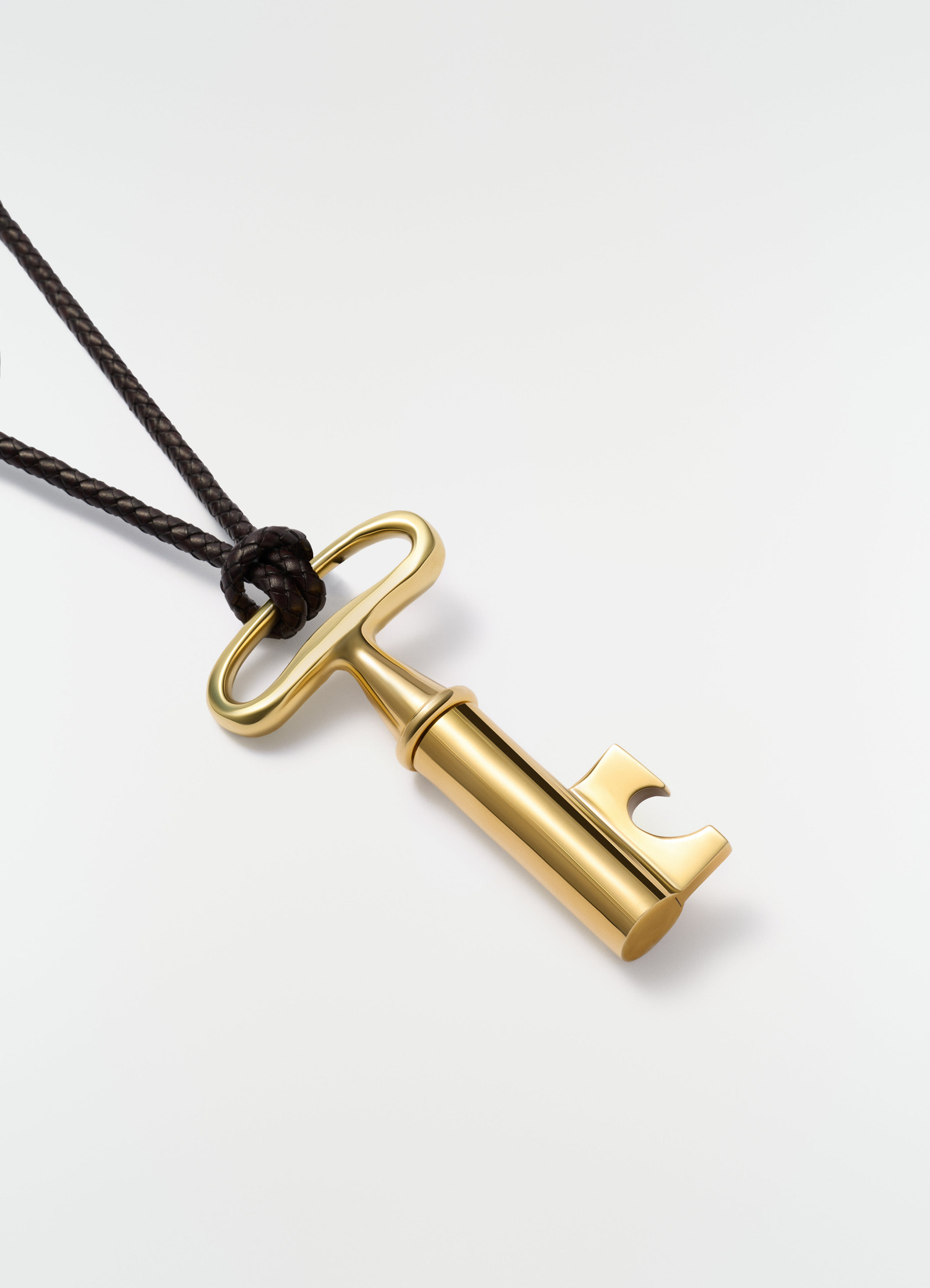 Auböck gold-tone stainless steel corkscrew charm on black braided leather cord lemaire close-up detail on white background