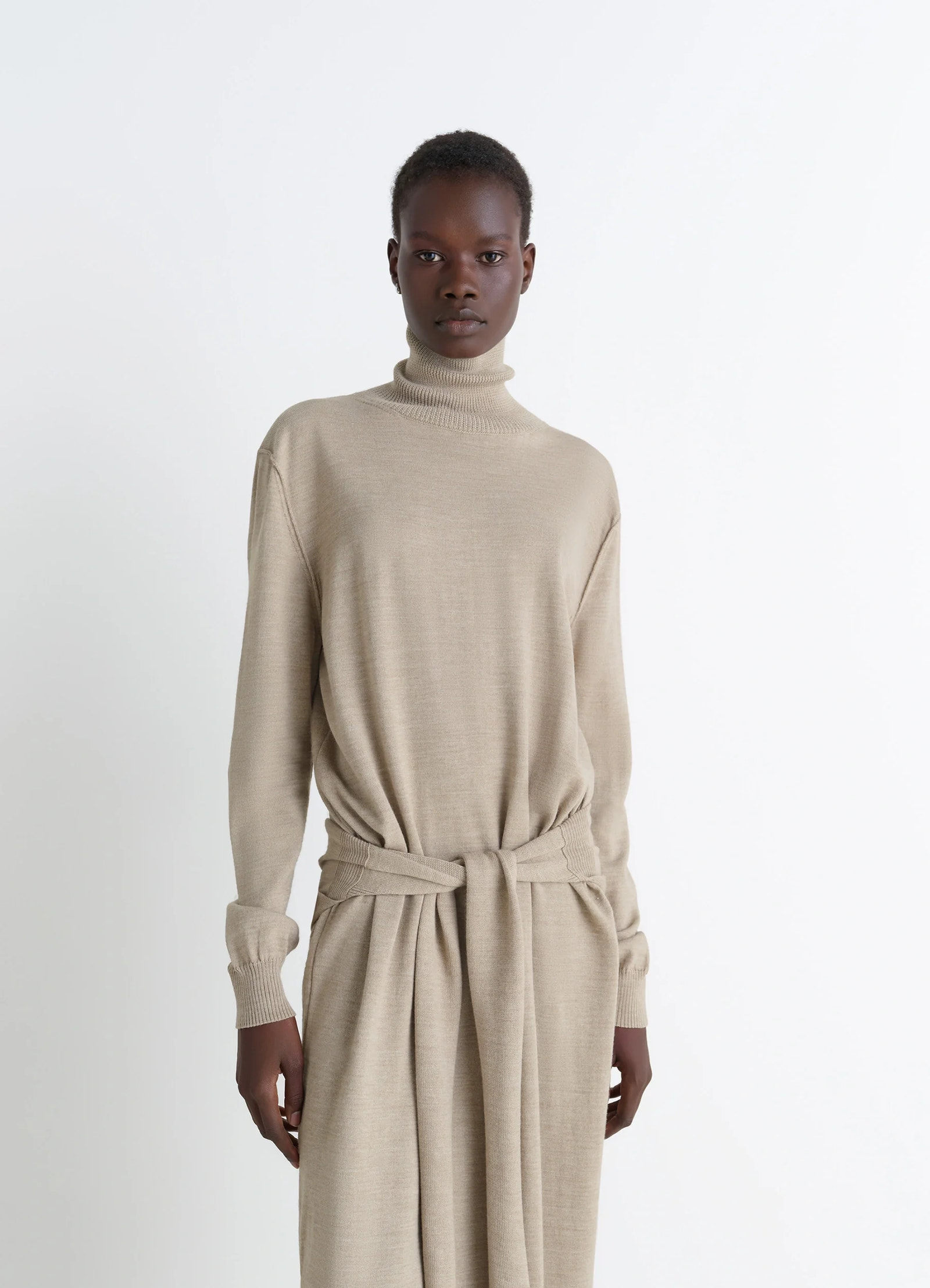 Lemaire trompe lœil dress in beige merino wool blend, model shot, three-quarter view high neckline, tie waist