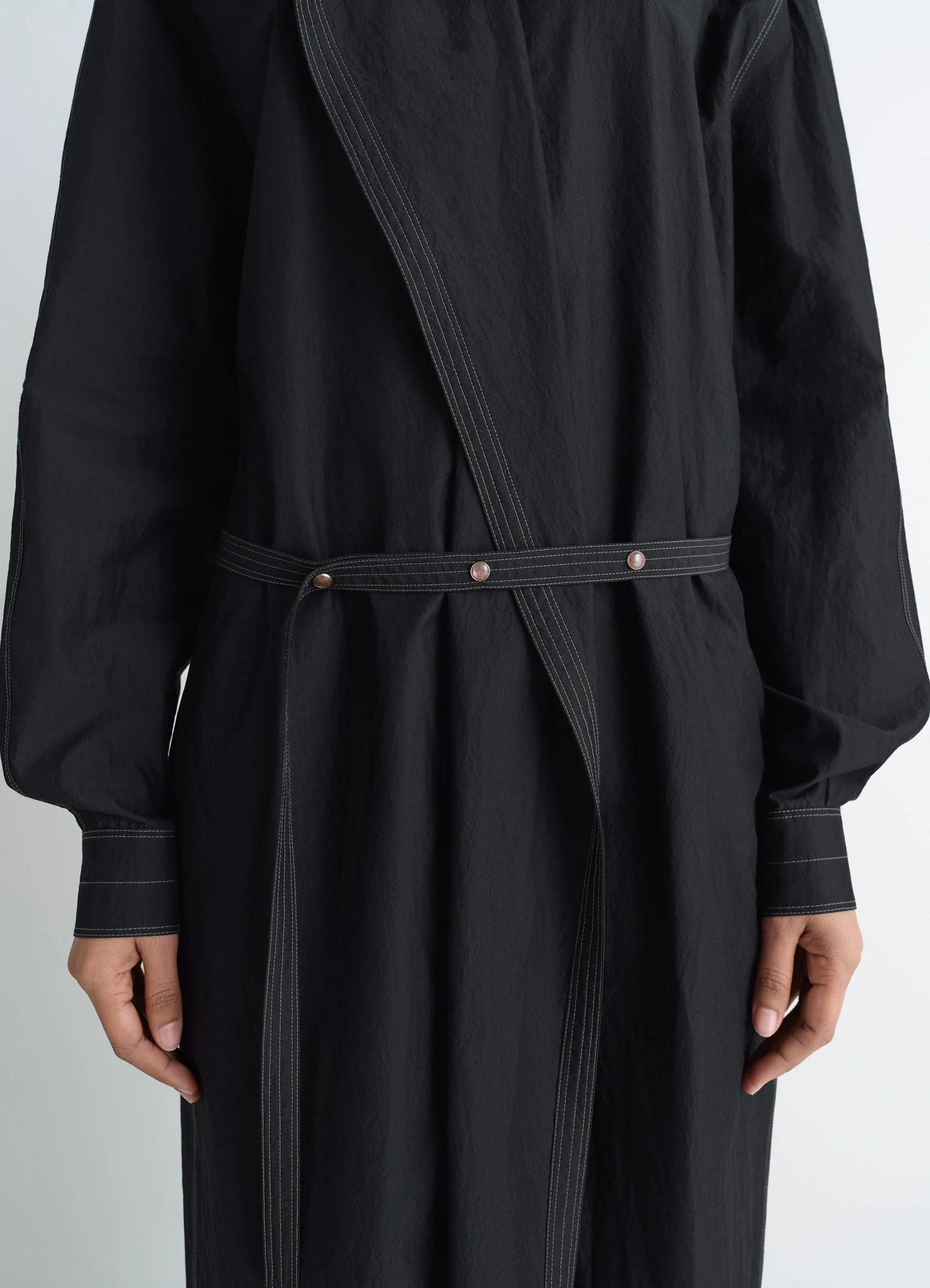 Asymmetrical shirt dress in black cotton crepe, model shot, close-up detail waist belt and stitching