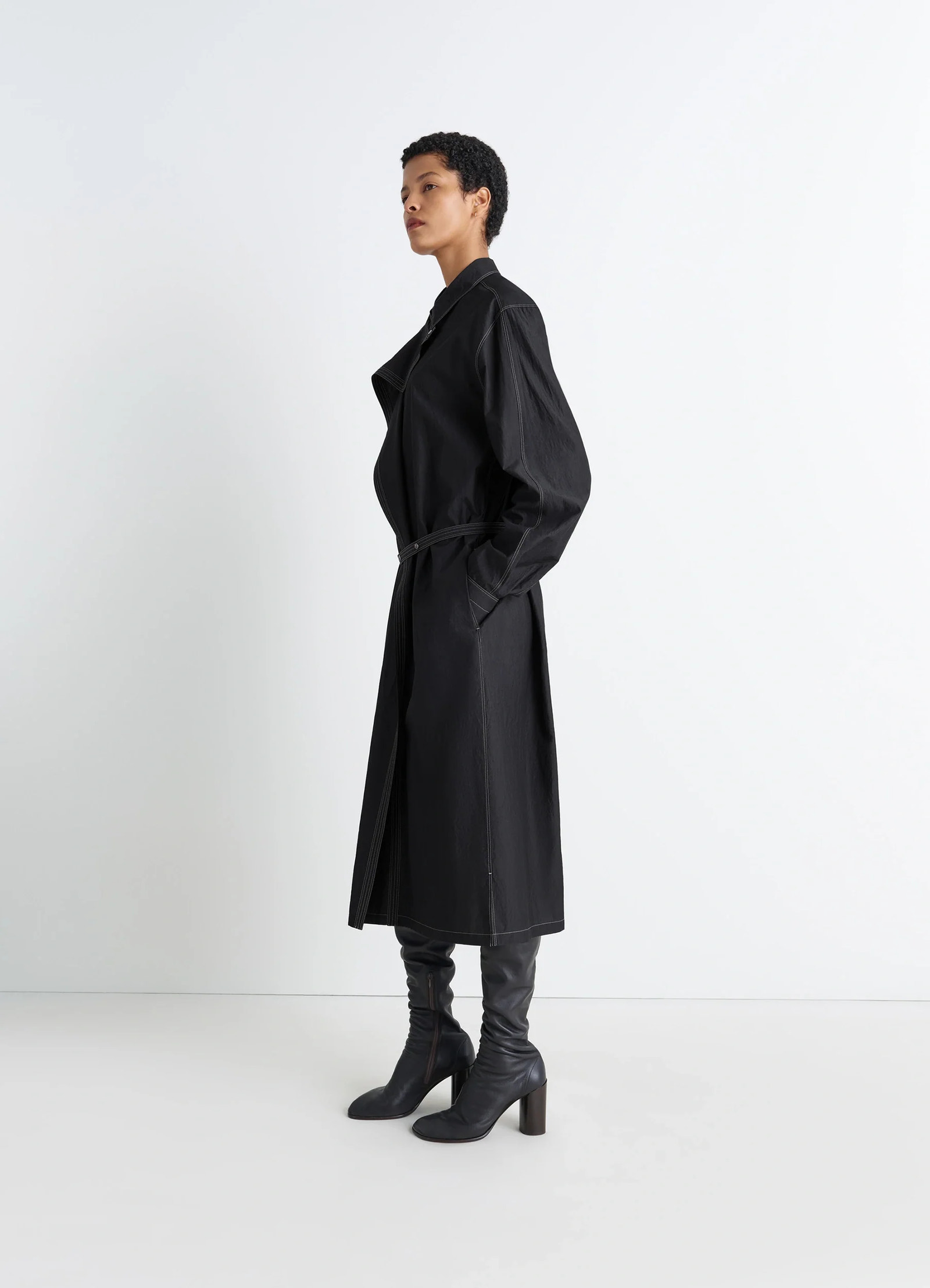 Asymmetrical shirt dress in black cotton crepe, model shot, side view loose sleeves, fitted waist