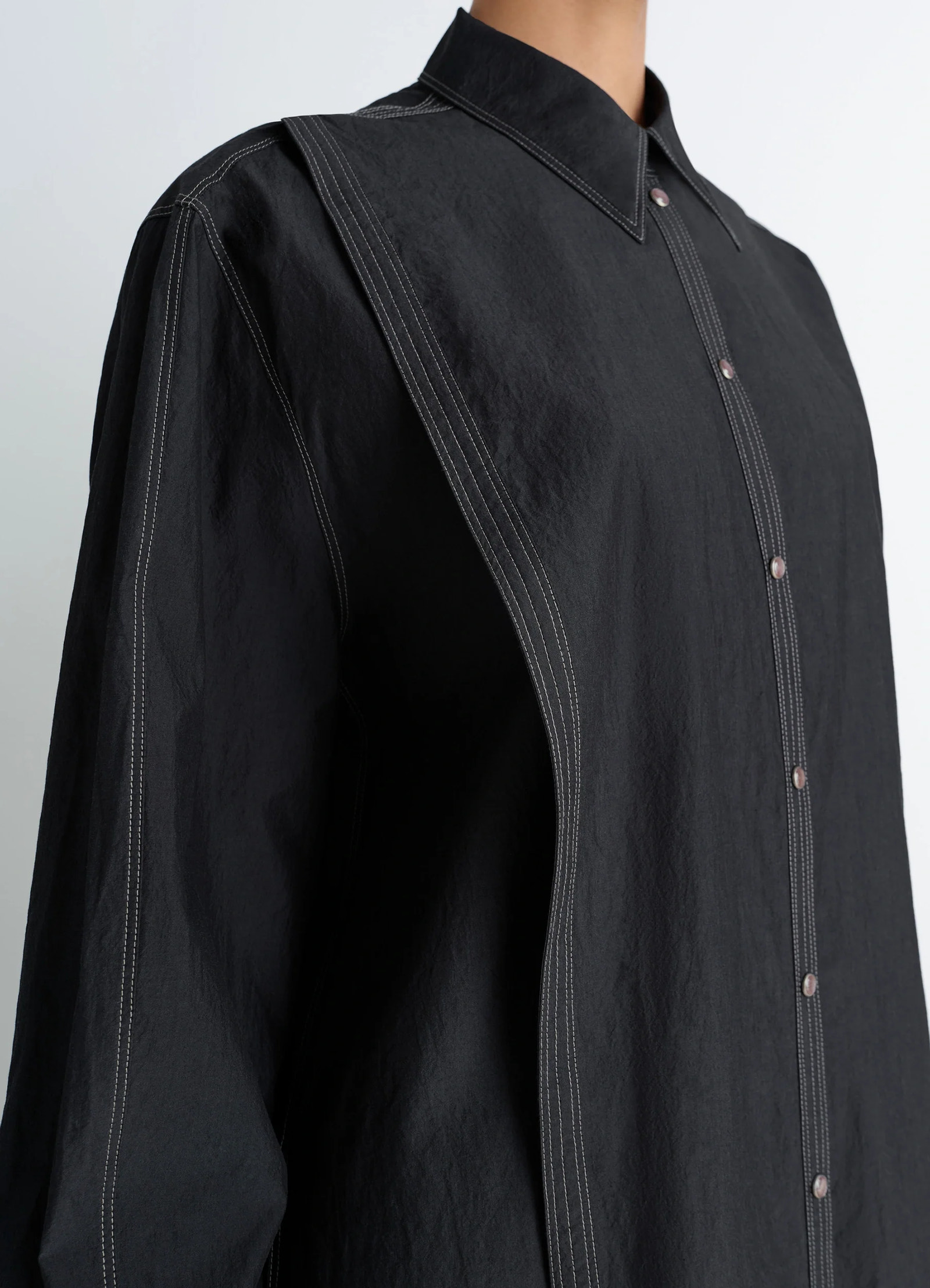 Asymmetrical shirt dress in black cotton crepe, model shot, upper body close-up button panel visible