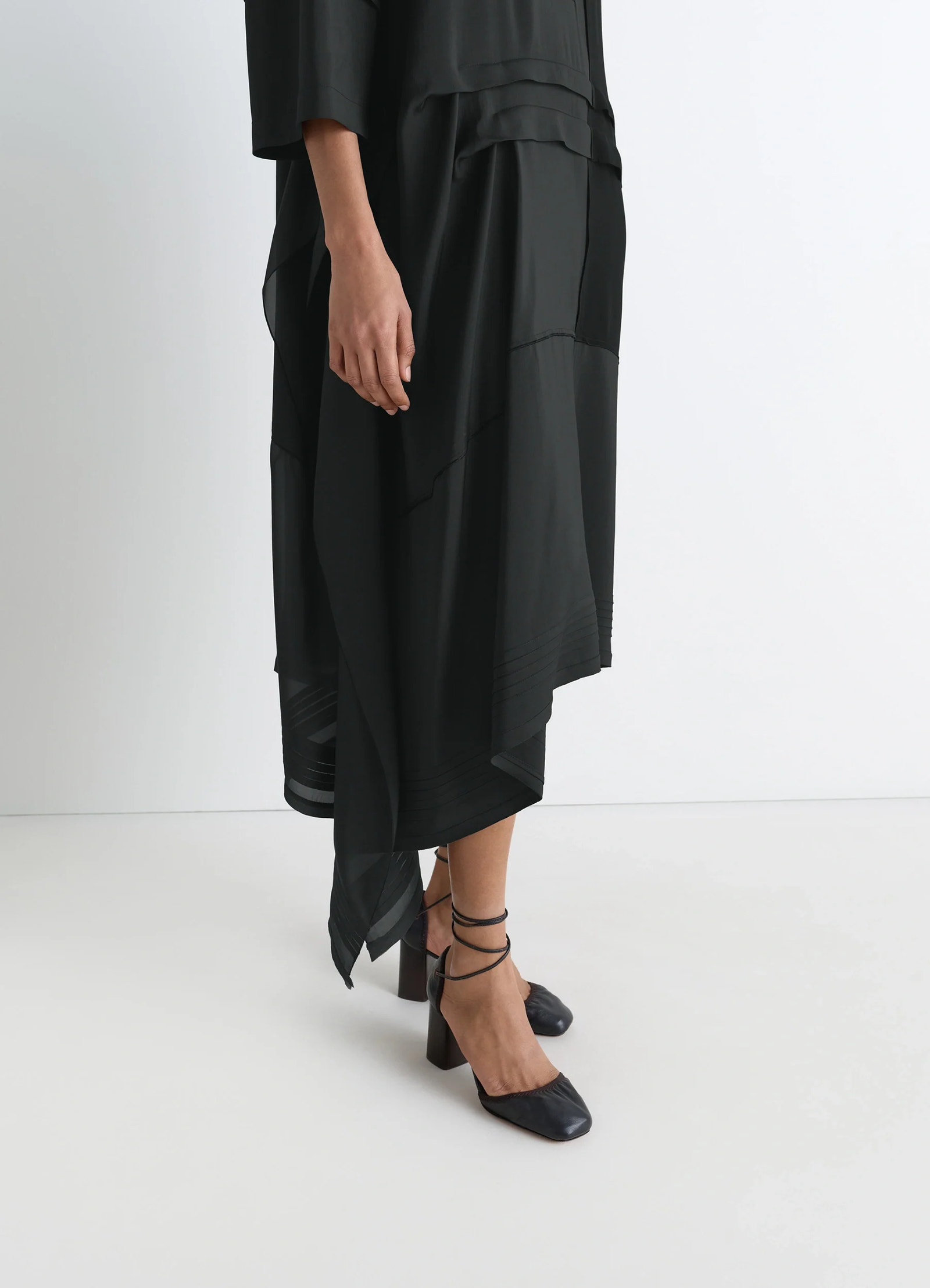 Blouse dress with pleats in black crêpe de chine, model shot, side lower view asymmetrical hemline