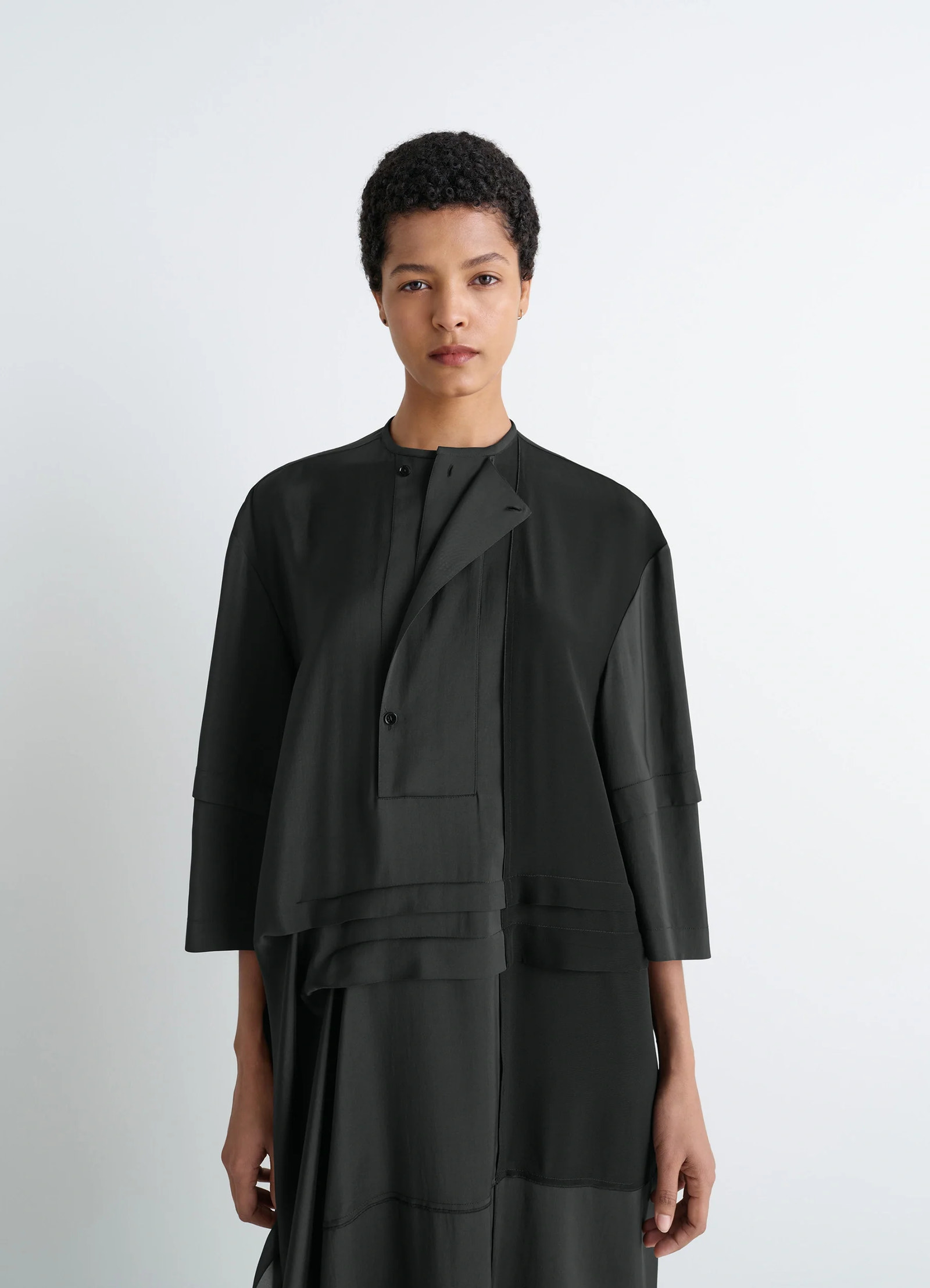 Blouse dress with pleats in black crêpe de chine, model shot, half front view pleated neckline detail