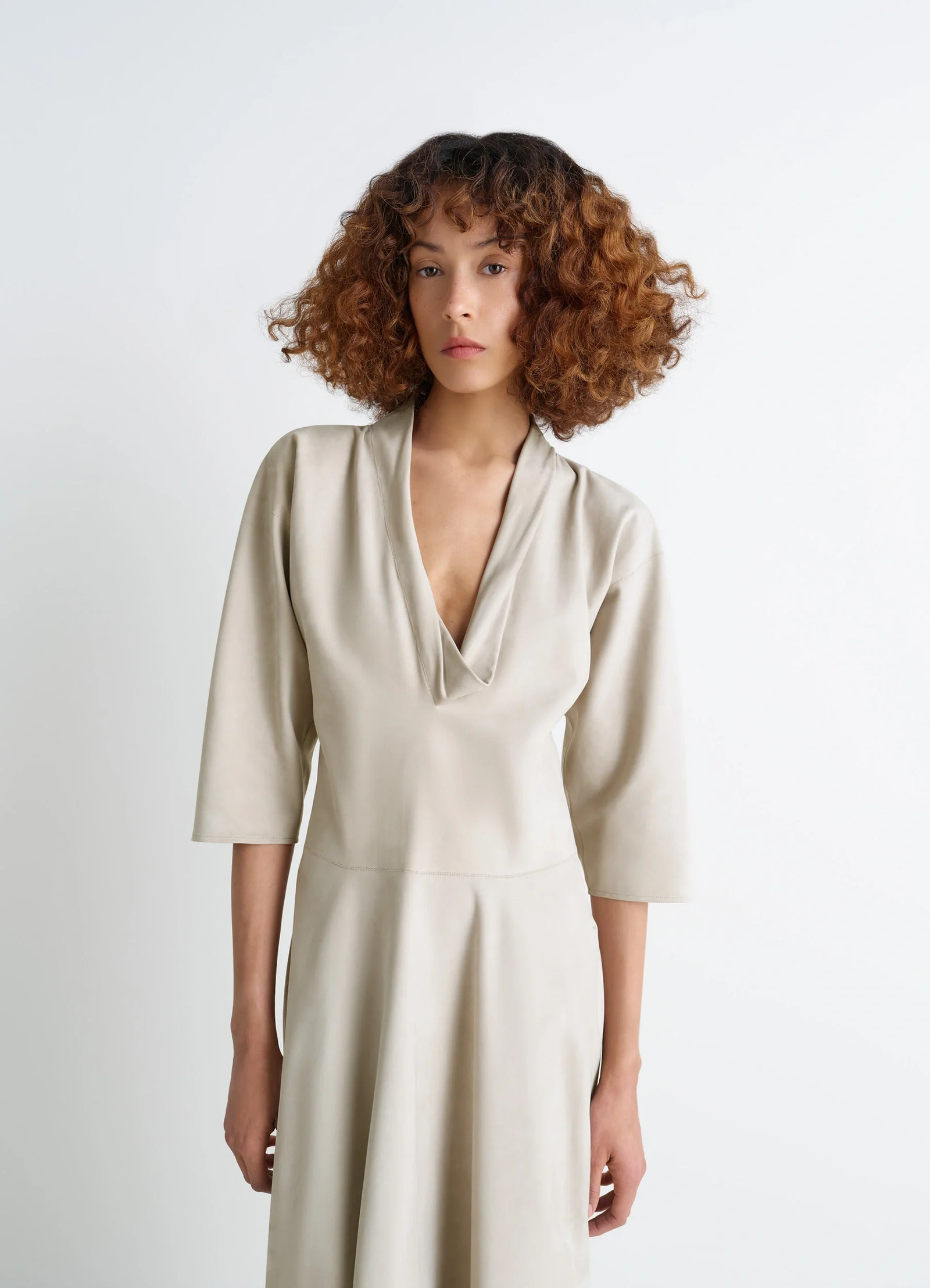 Leather v-neck dress in nubuck leather, model shot, three-quarter view draped sleeves