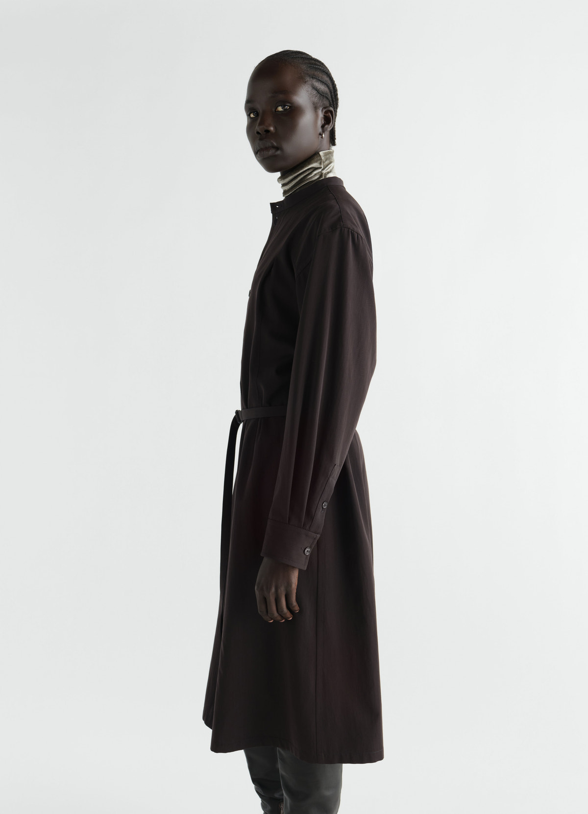 Belted dark brown wool gabardine dress by lemaire worn by model side view with high collar background