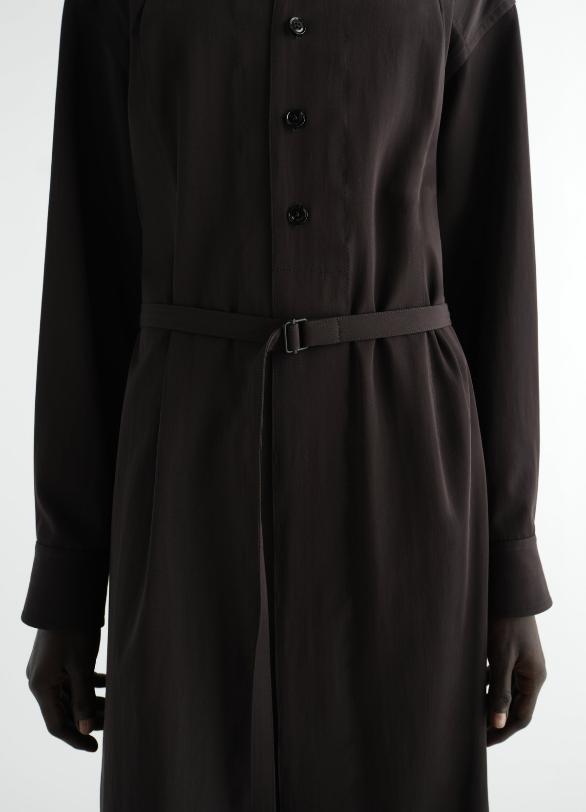 Belted dark brown wool gabardine dress by lemaire worn by model front close-up with buttons and slim belt