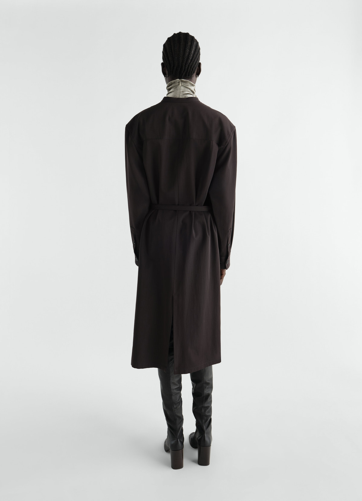 Belted dark brown wool gabardine dress lemaire rear view worn by model with grey turtleneck and black boots