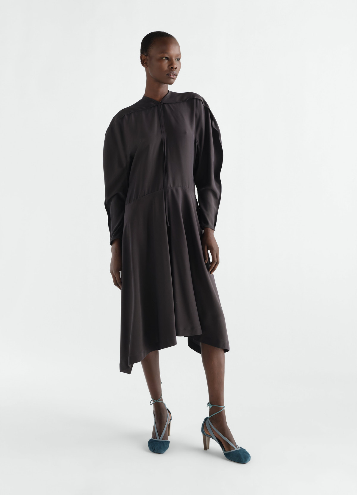 Midi dress in black silk viscose cloth lemaire worn by a model front view with asymmetric hem and long sleeves