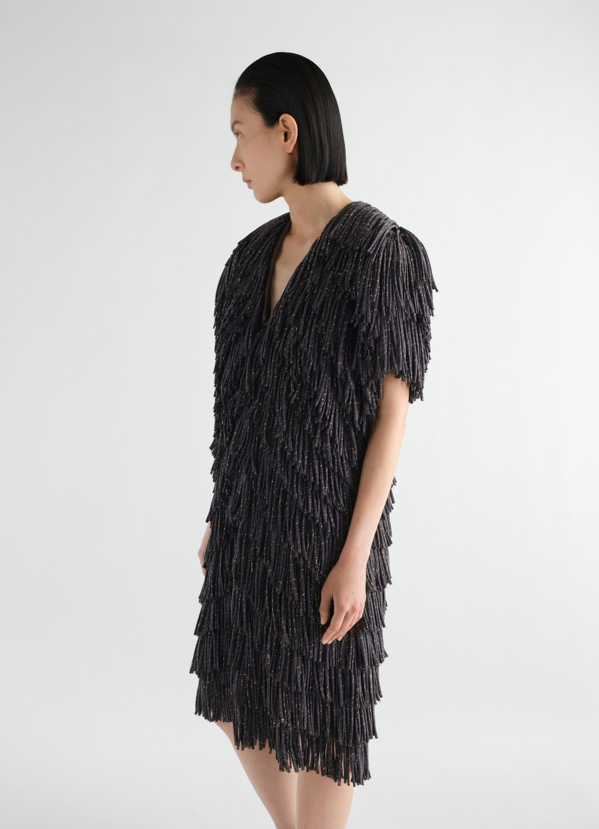 Fringed black snake print dry silk dress by lemaire worn by model side view with layered fringes