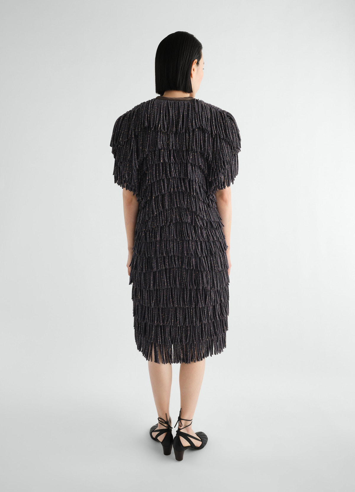 Fringed black snake printed dry silk dress by lemaire worn by model back view on plain white background