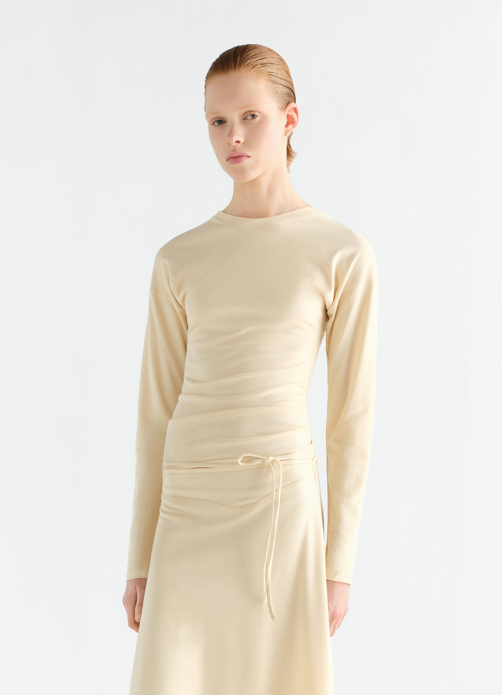 Fluid long-sleeve beige jersey crepe dress with waist tie worn by model lemaire front view